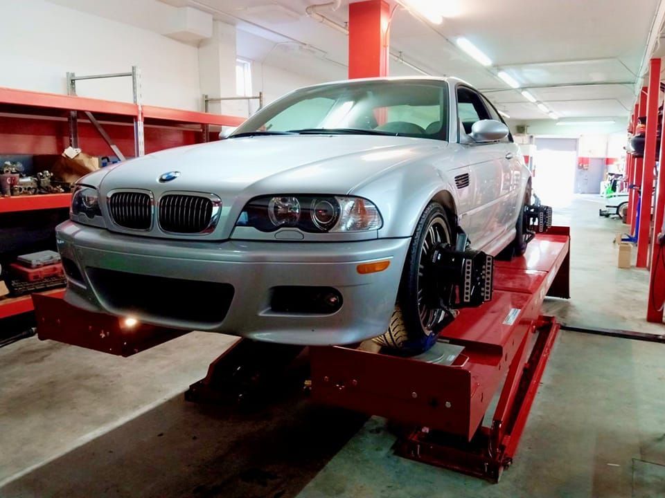 A silver bmw is sitting on a red lift in a garage.