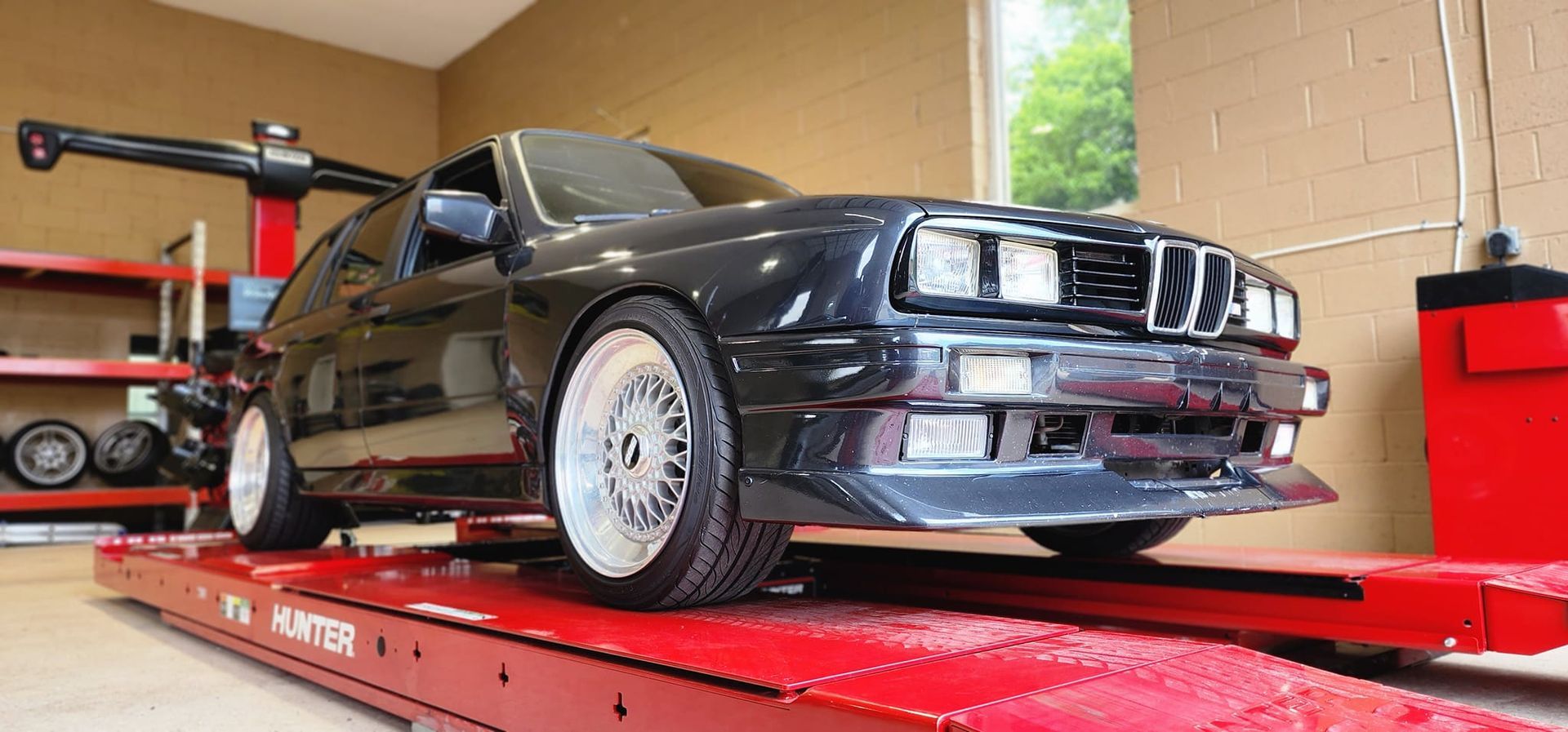 A black car is sitting on top of a red ramp in a garage.