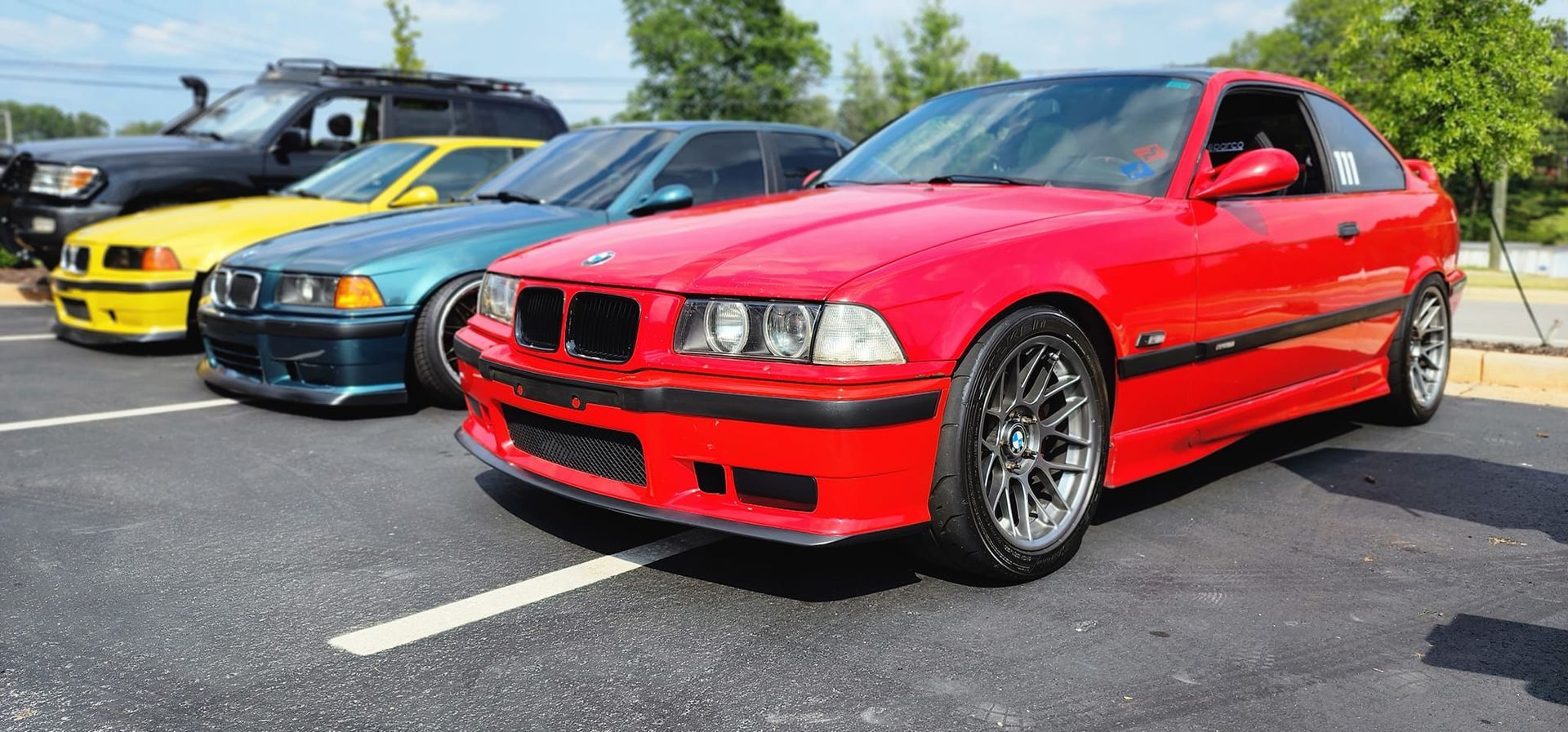 A row of red cars are parked in a parking lot.