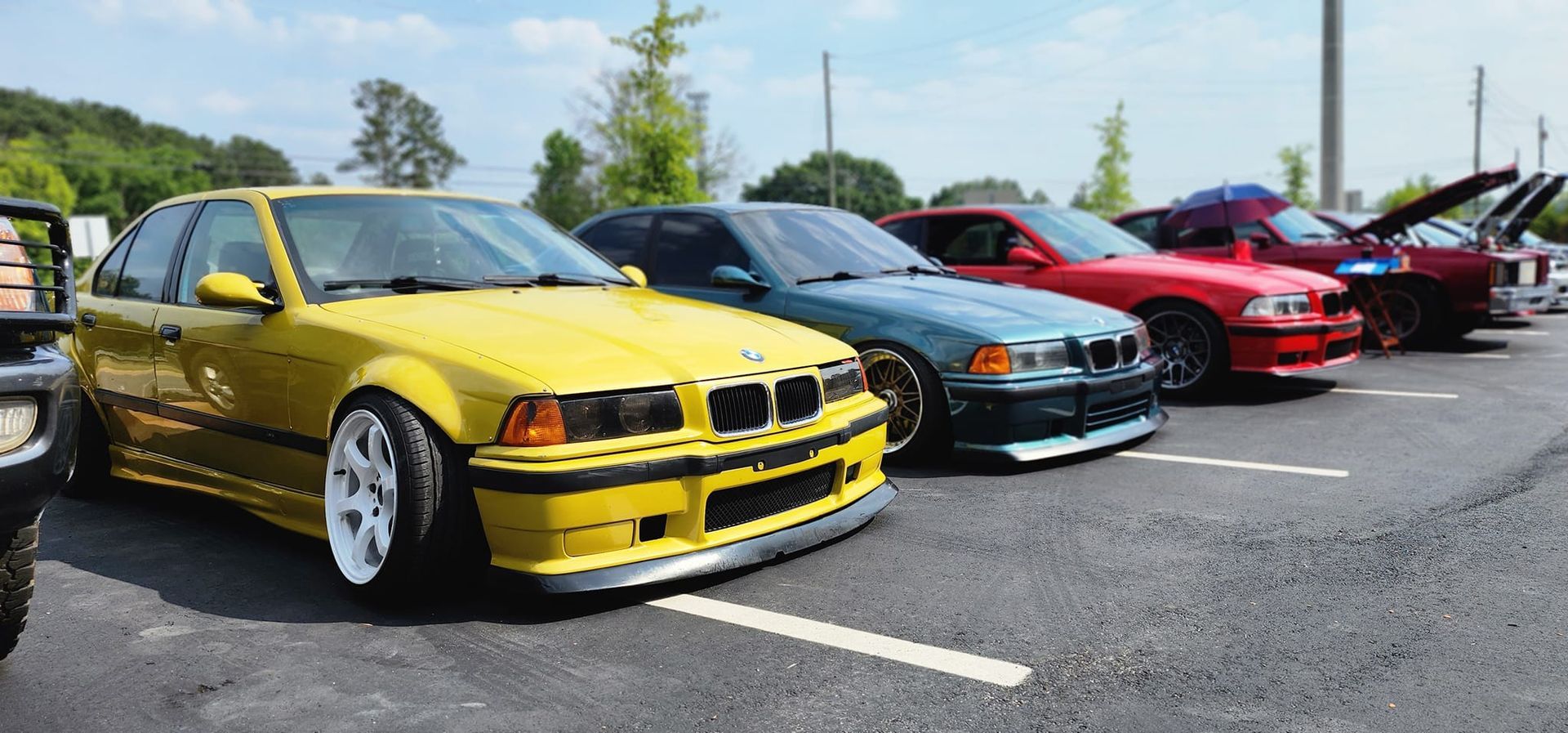A row of cars are parked in a parking lot.
