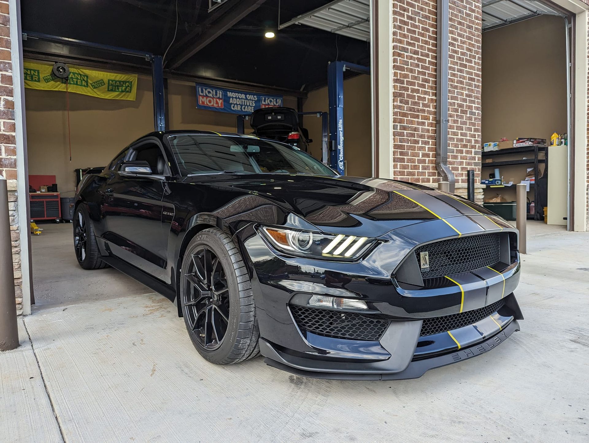 A black ford mustang is parked in a garage.