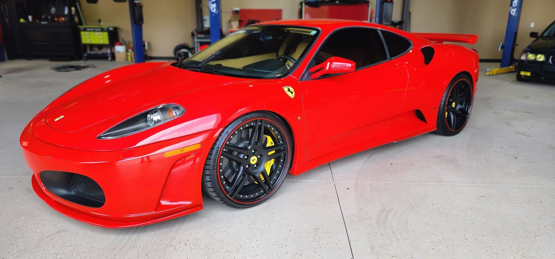 A red ferrari f430 is parked in a garage.