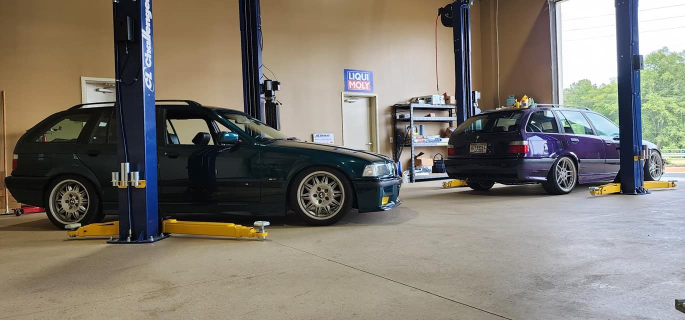 Two cars are parked on a lift in a garage.
