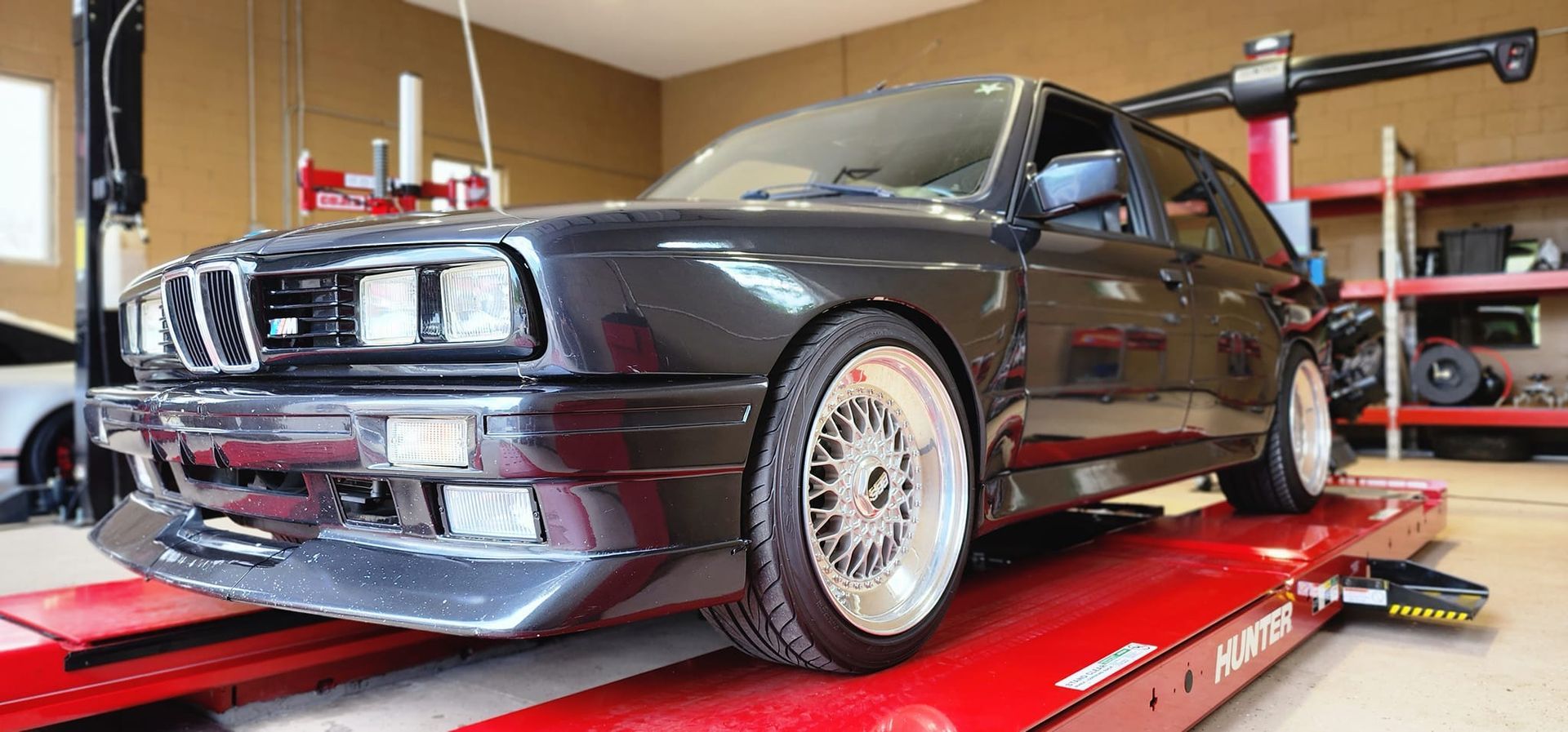 A black car is sitting on top of a red lift in a garage.