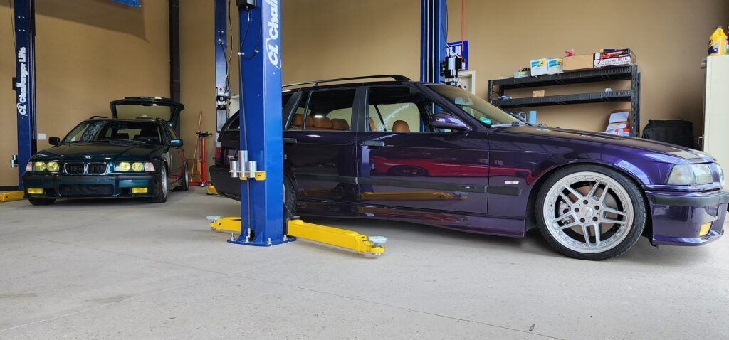 A purple car is parked on a lift in a garage.