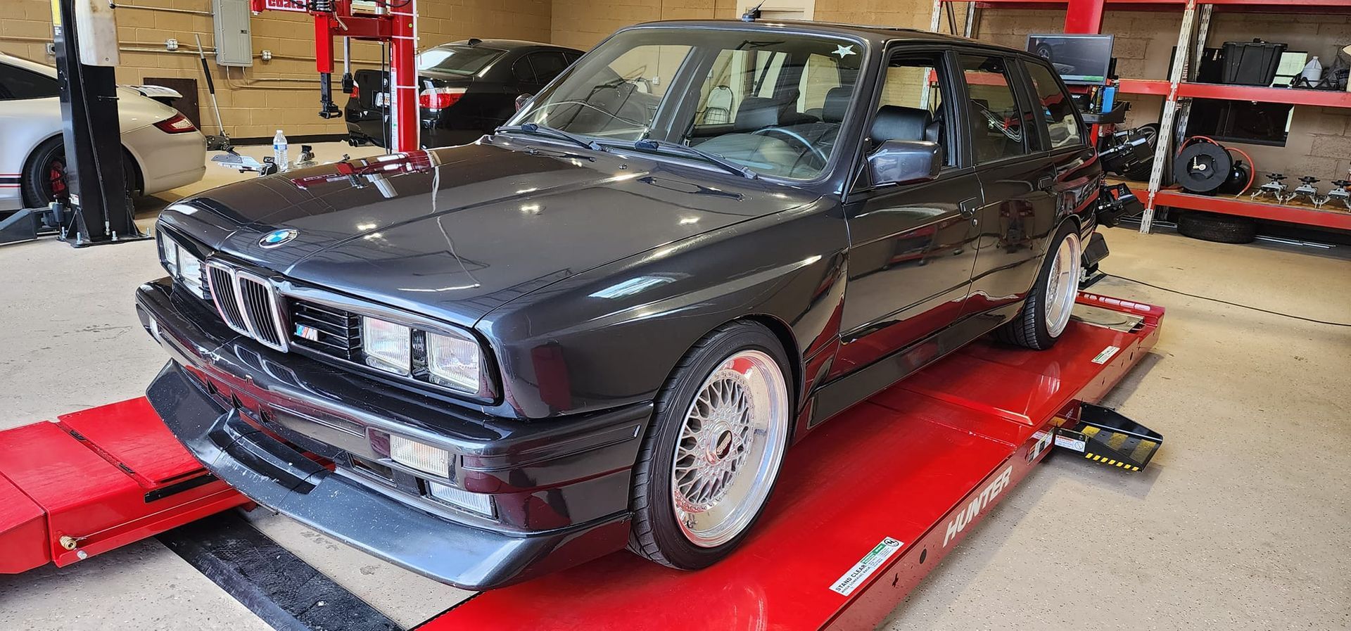 A black car is sitting on top of a red ramp in a garage.