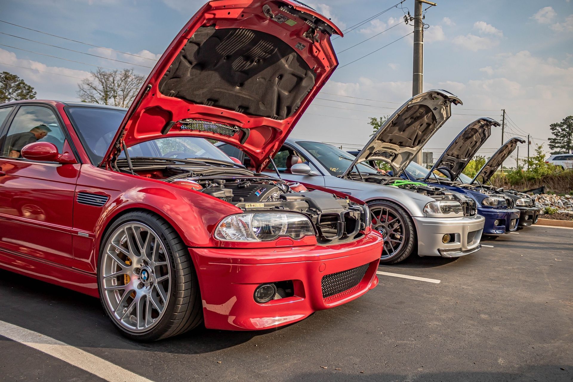 A row of cars parked next to each other with their hoods open.