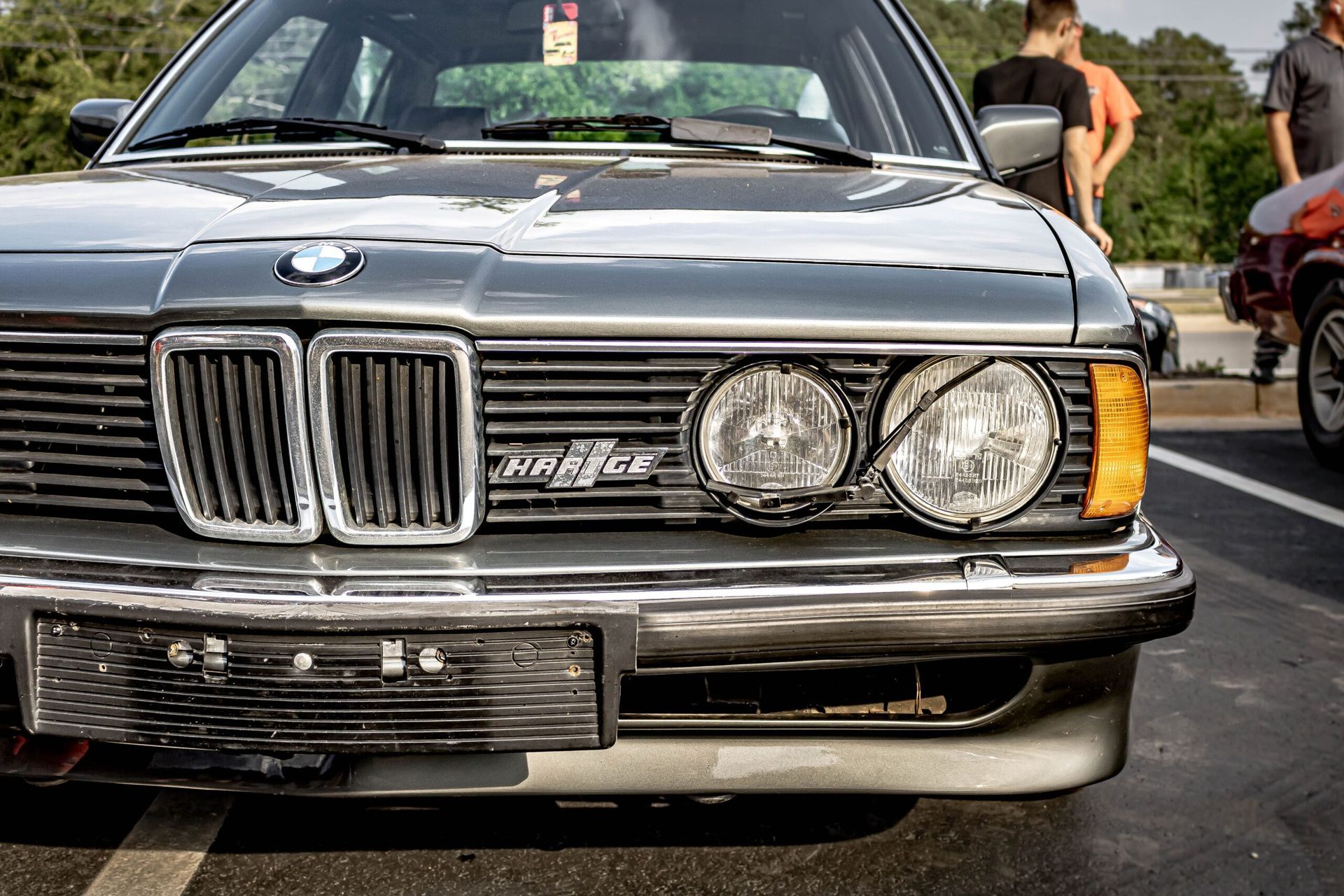 A bmw is parked in a parking lot next to a motorcycle.