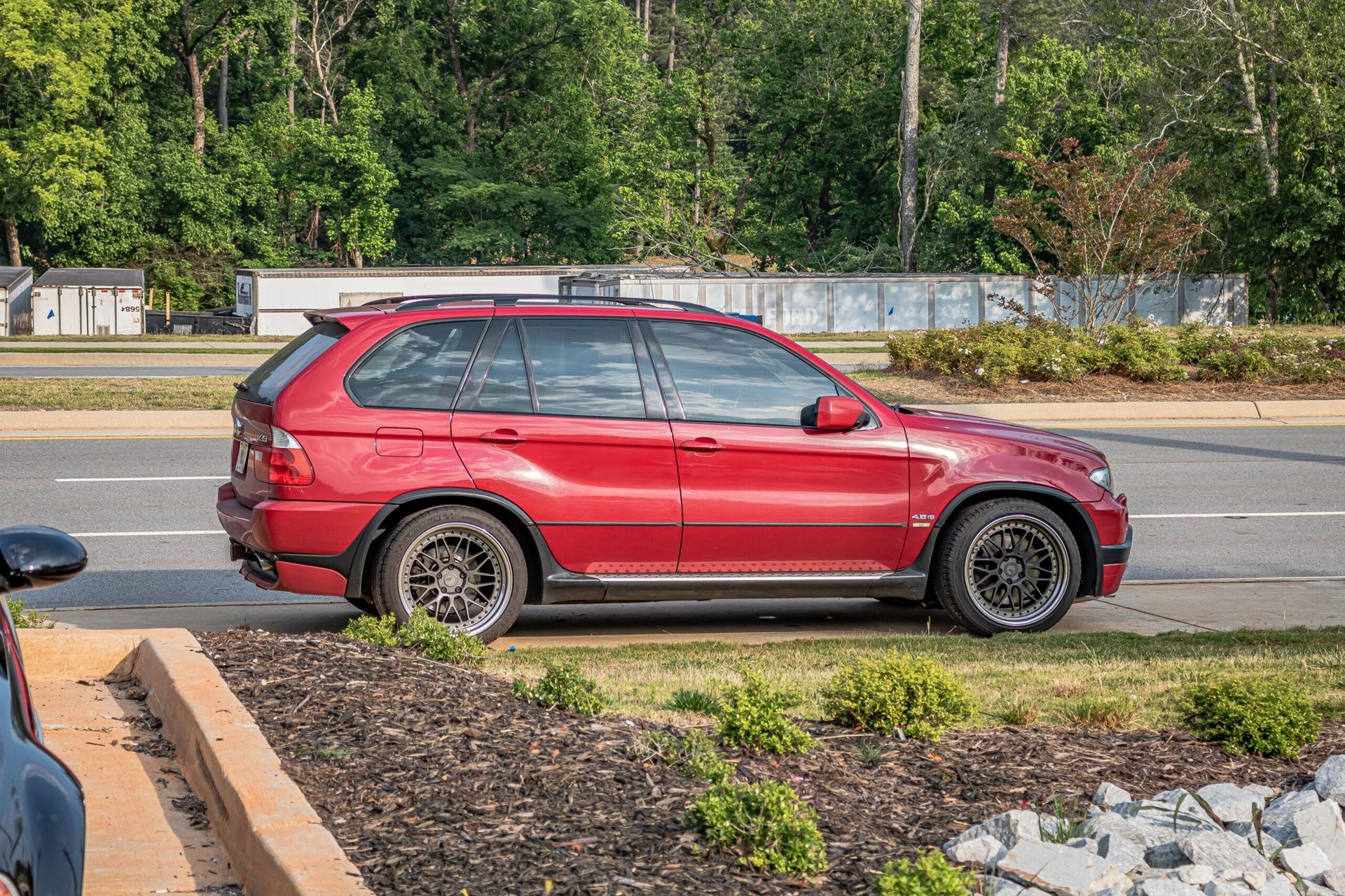 A red bmw x5 is parked on the side of the road.