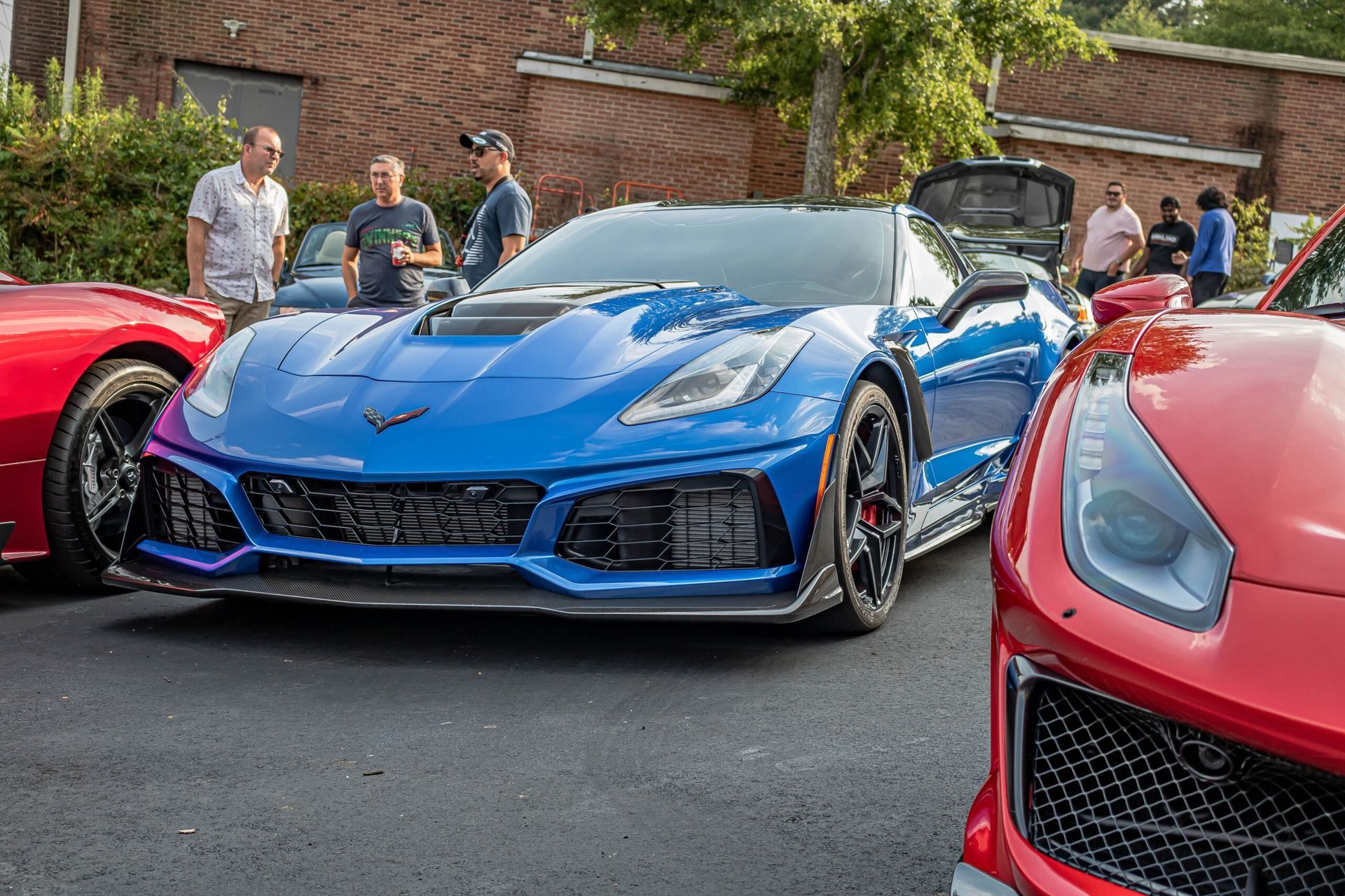 A blue corvette is parked next to a red corvette at a car show.