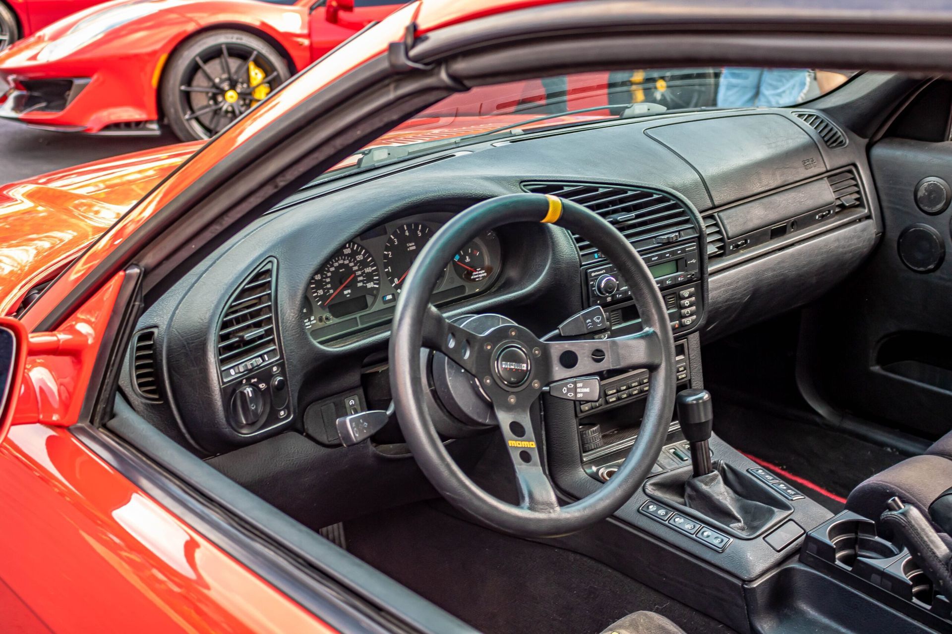 The interior of a red sports car with a steering wheel and dashboard.