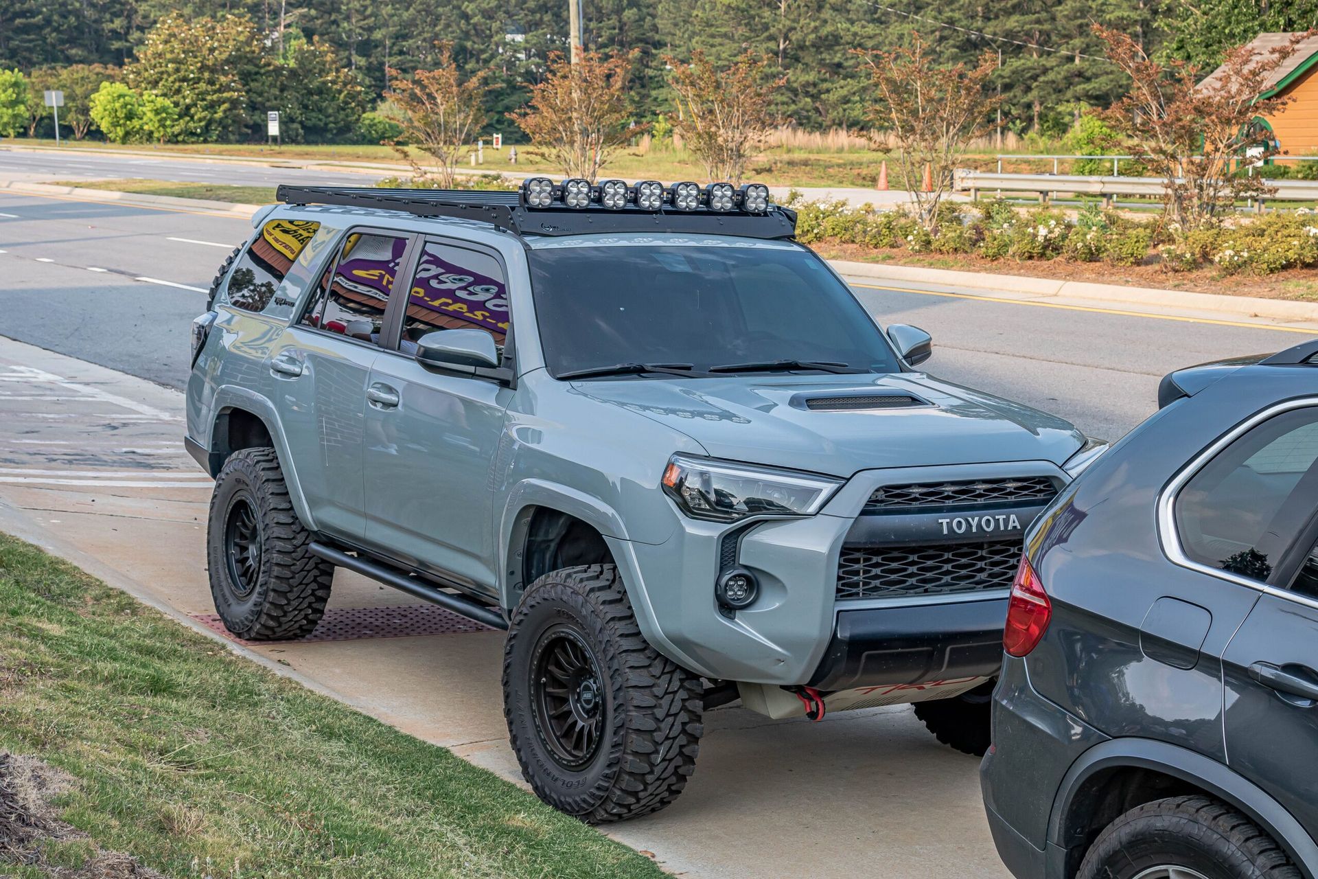 A toyota 4runner with a roof rack is parked on the side of the road next to another car.
