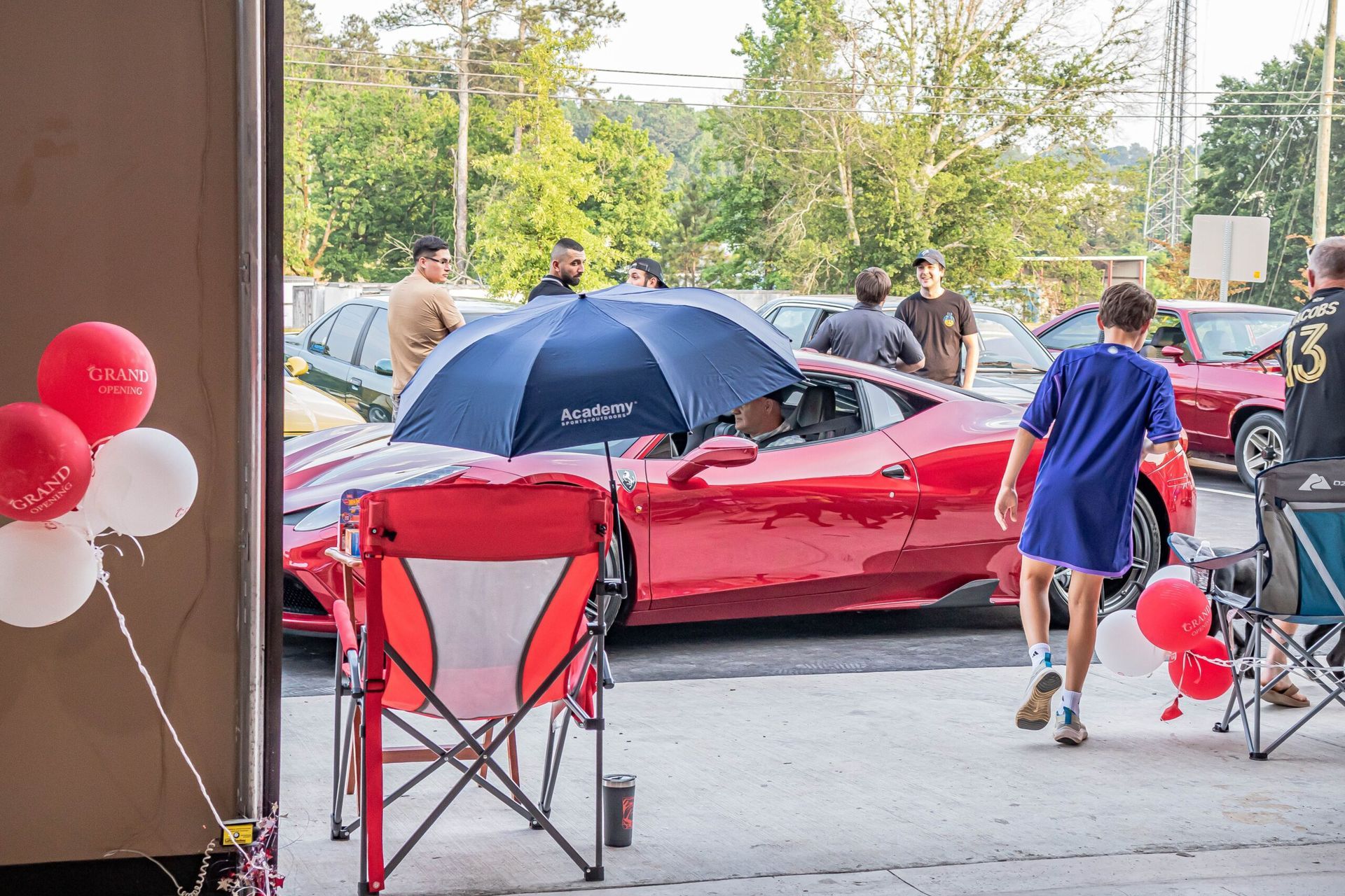 A group of people are standing around a red sports car.