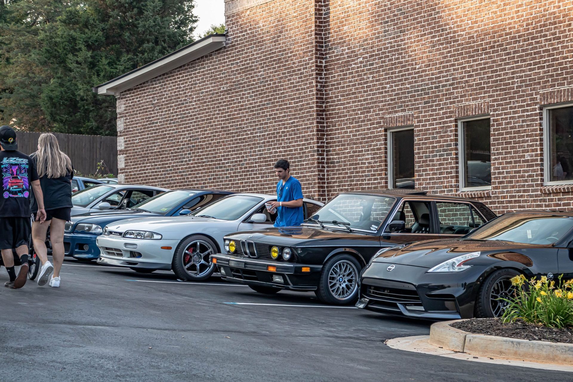 A row of cars are parked in front of a brick building.