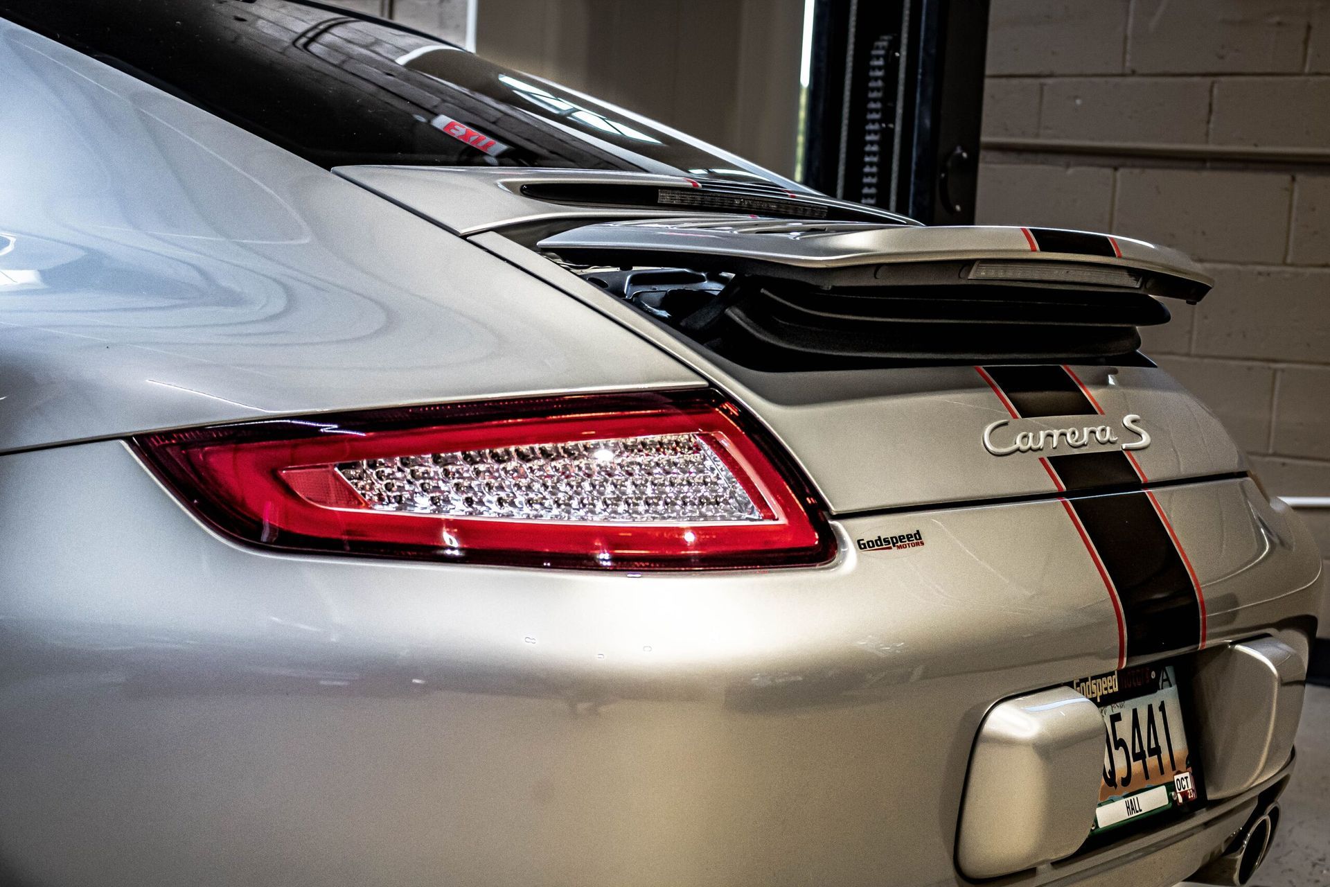 The rear end of a silver porsche carrera