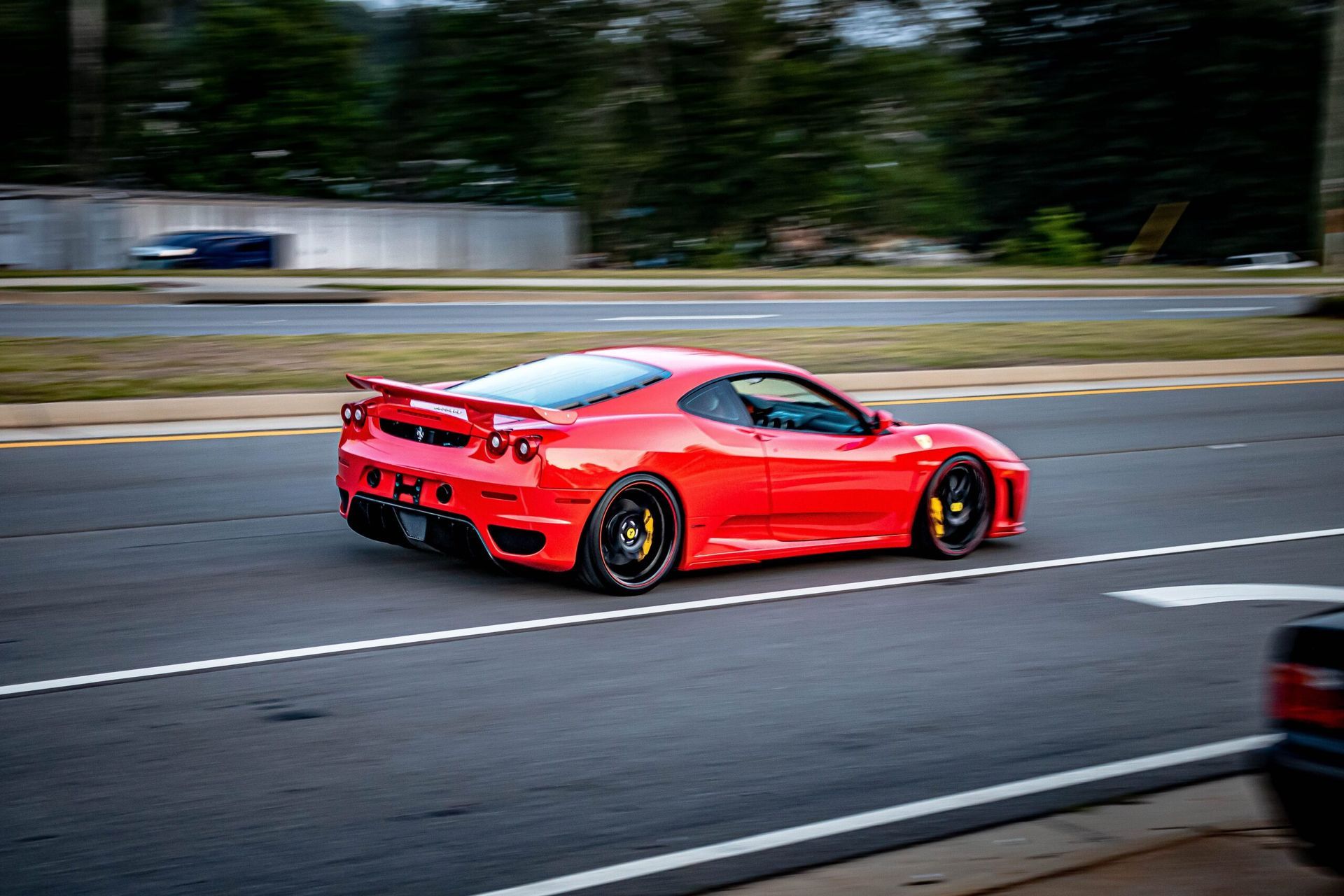 A red sports car is driving down a street.