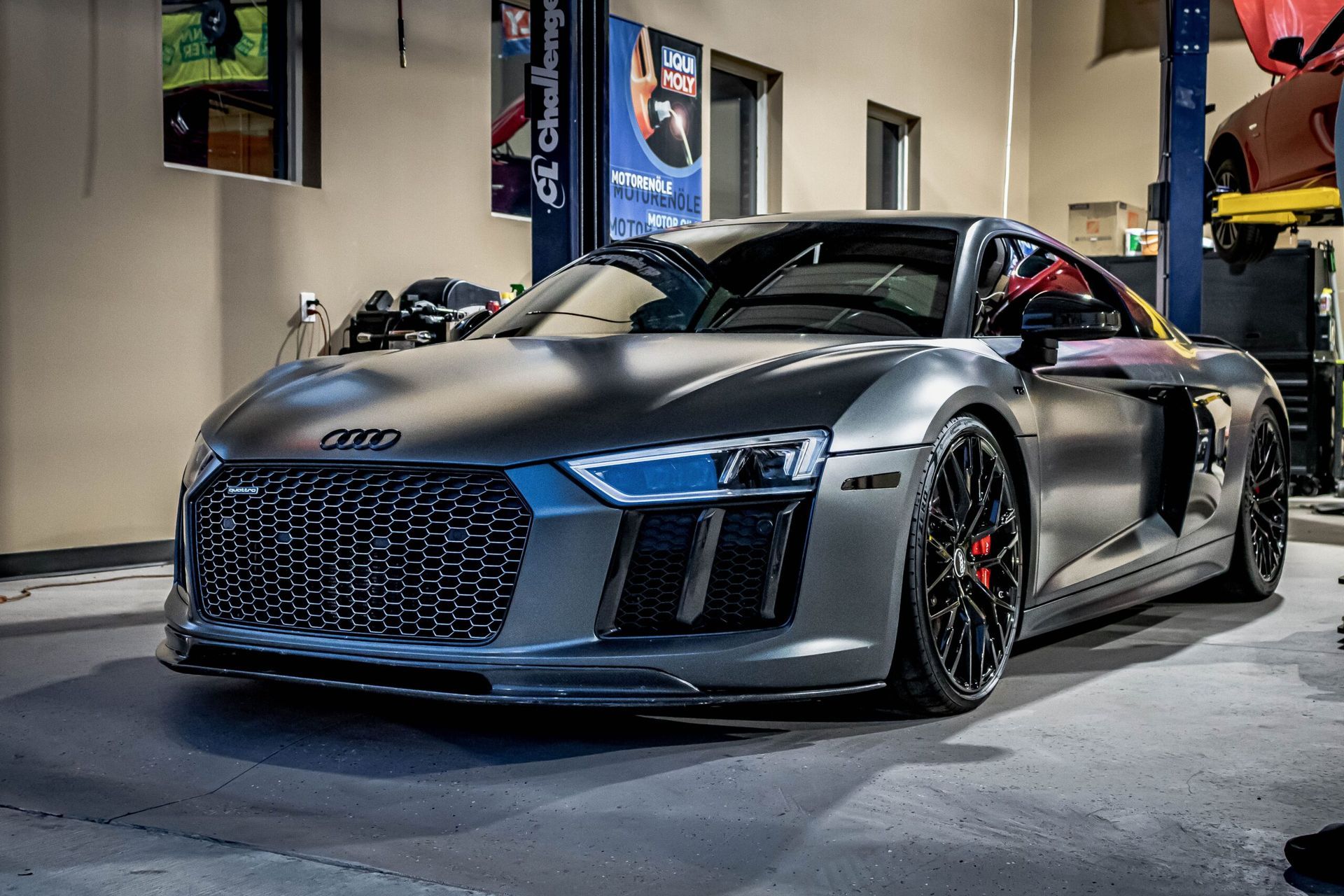 A silver audi r8 is parked in a garage.