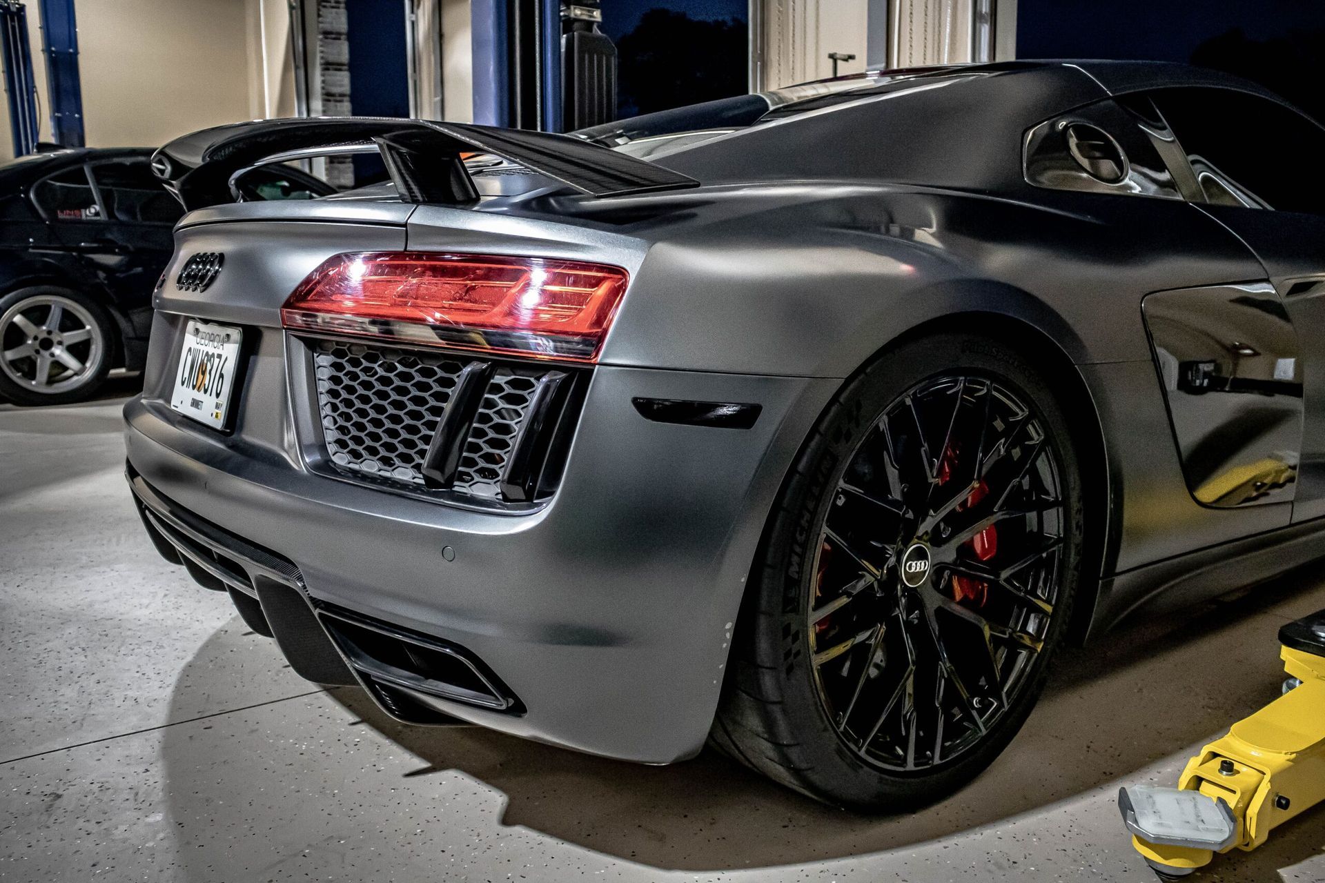 A silver audi r8 is parked in a garage