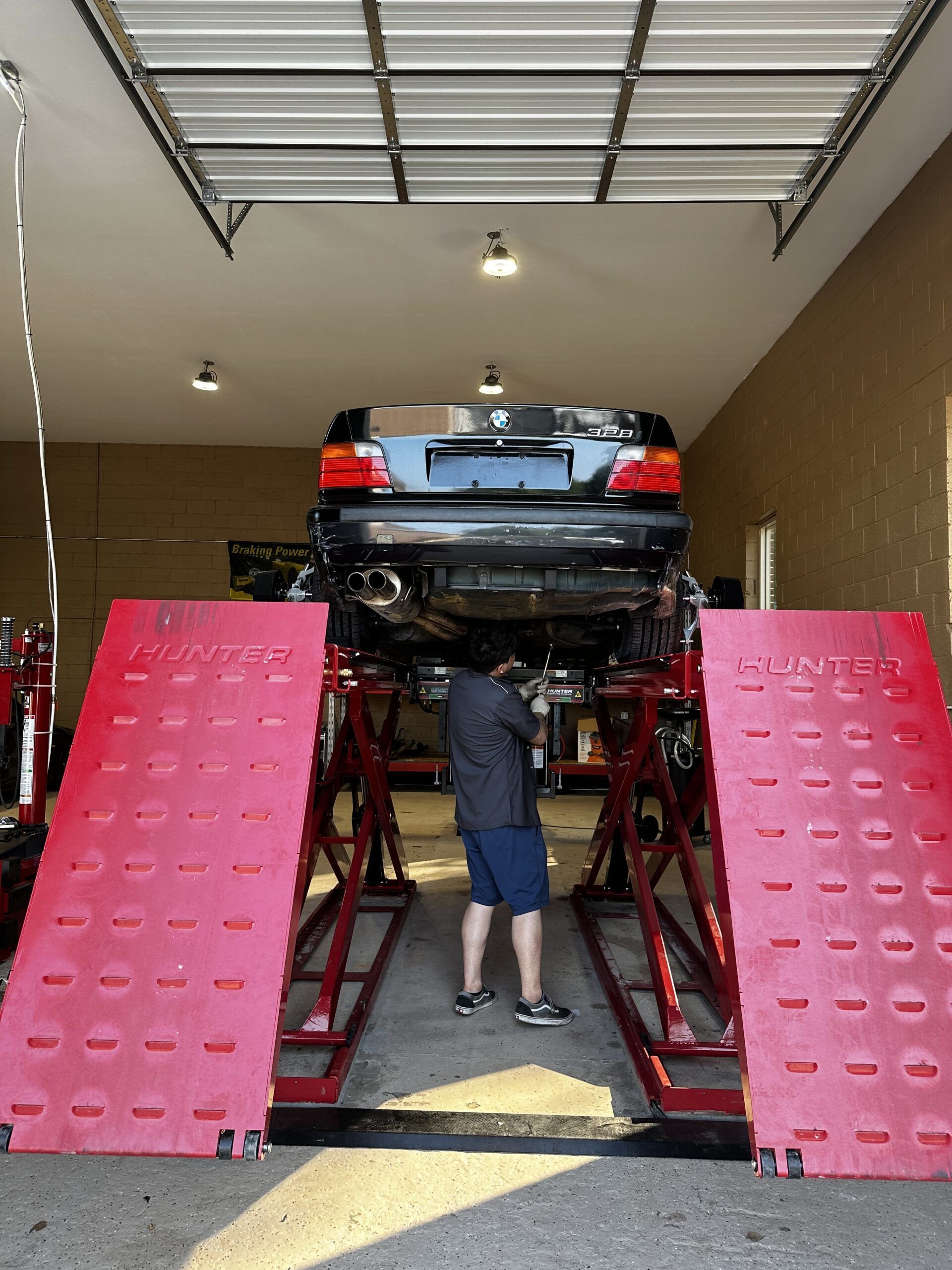A man is working on a car on a lift in a garage