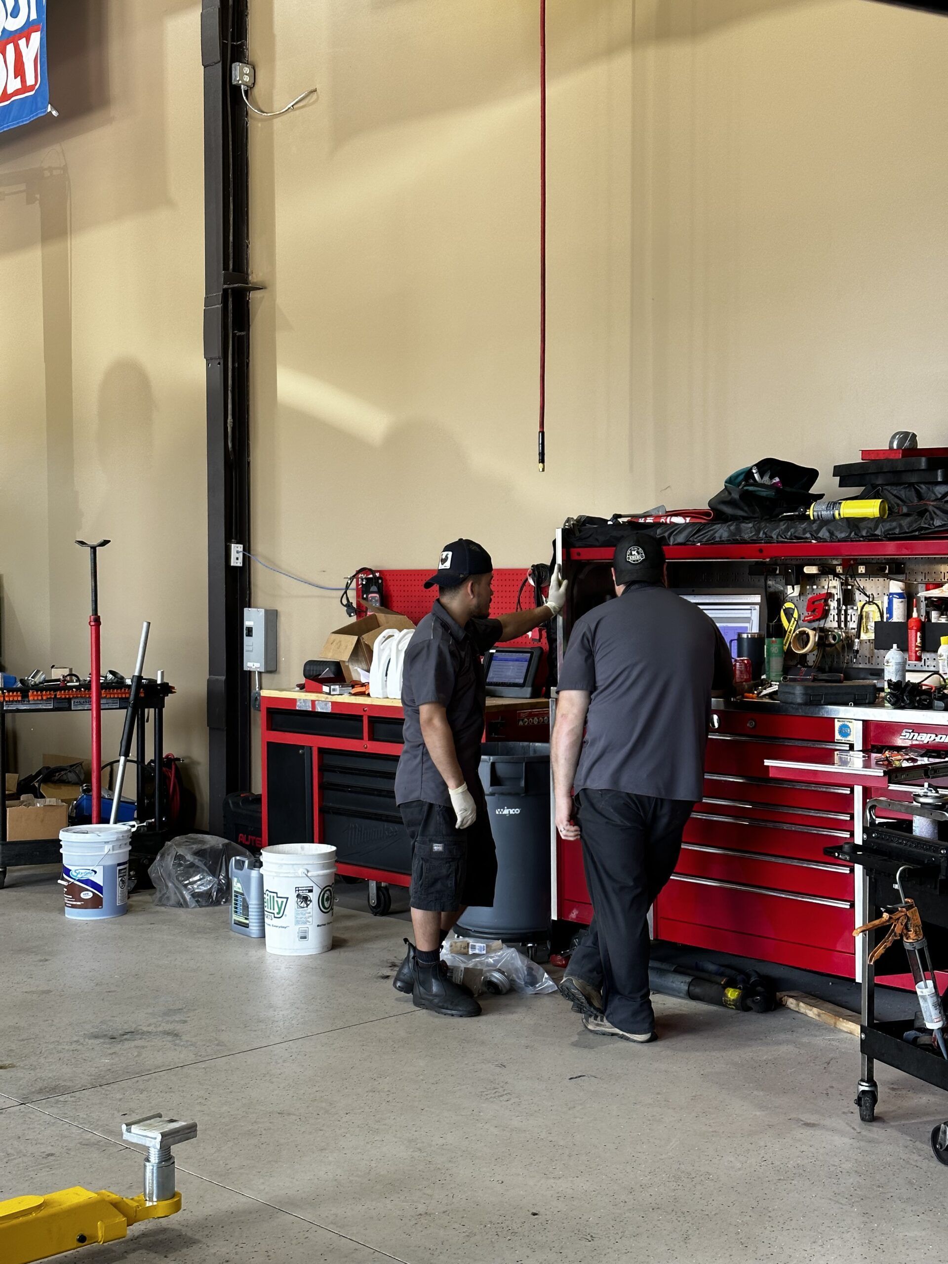 Two men are working in a garage with a liqui moly sign above them