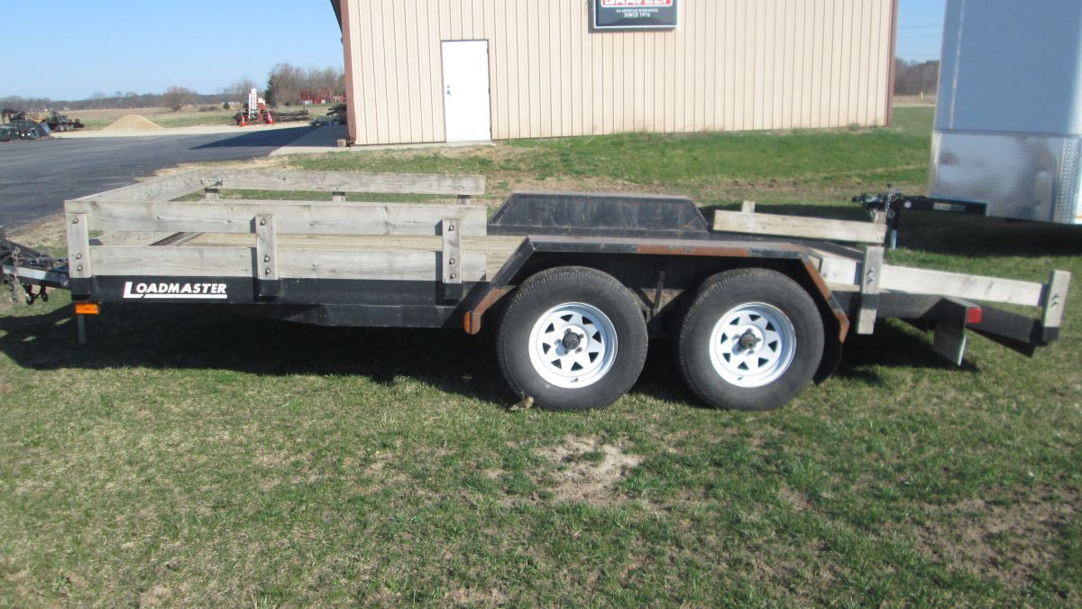 A trailer is parked in a grassy field in front of a building.