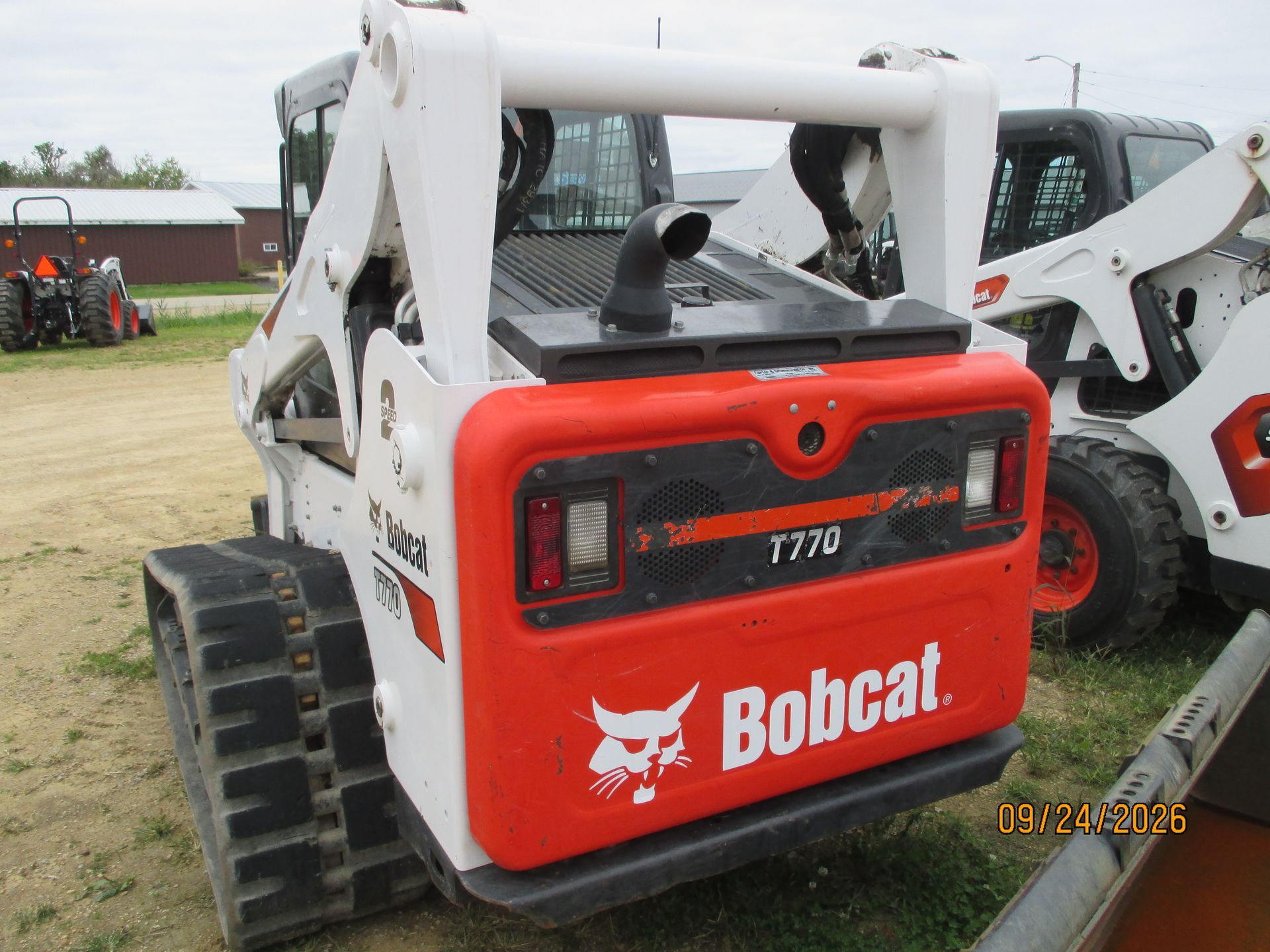 Bobcat T770 compact track loader with white arms and red rear panel in a dirt lot
