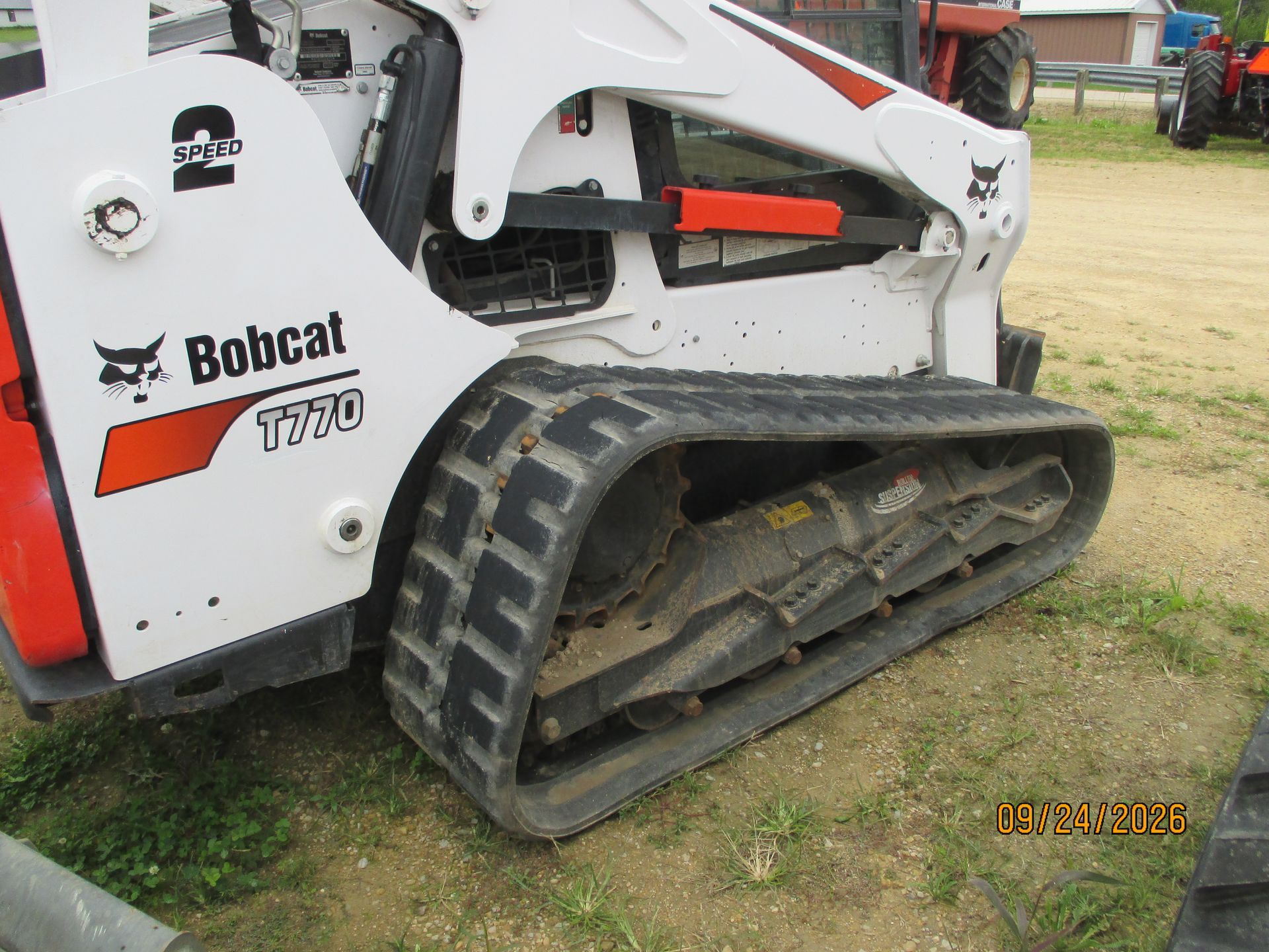 White Bobcat T770 compact track loader with black tracks parked on grass in a rural yard