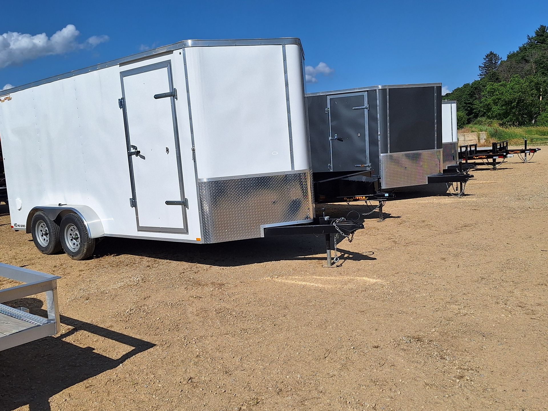 A row of trailers are parked in a dirt field.