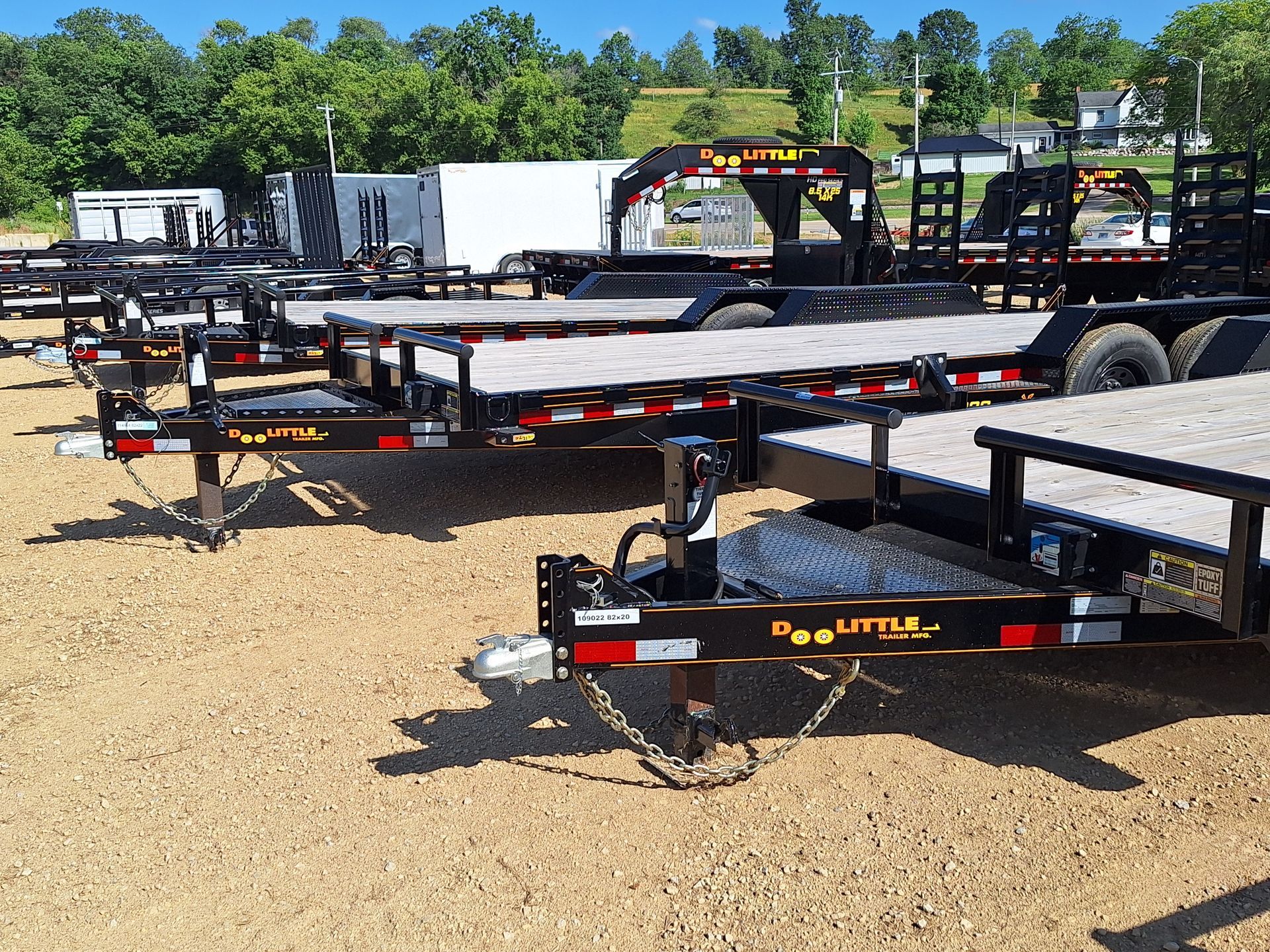 A row of trailers are parked in a dirt lot.