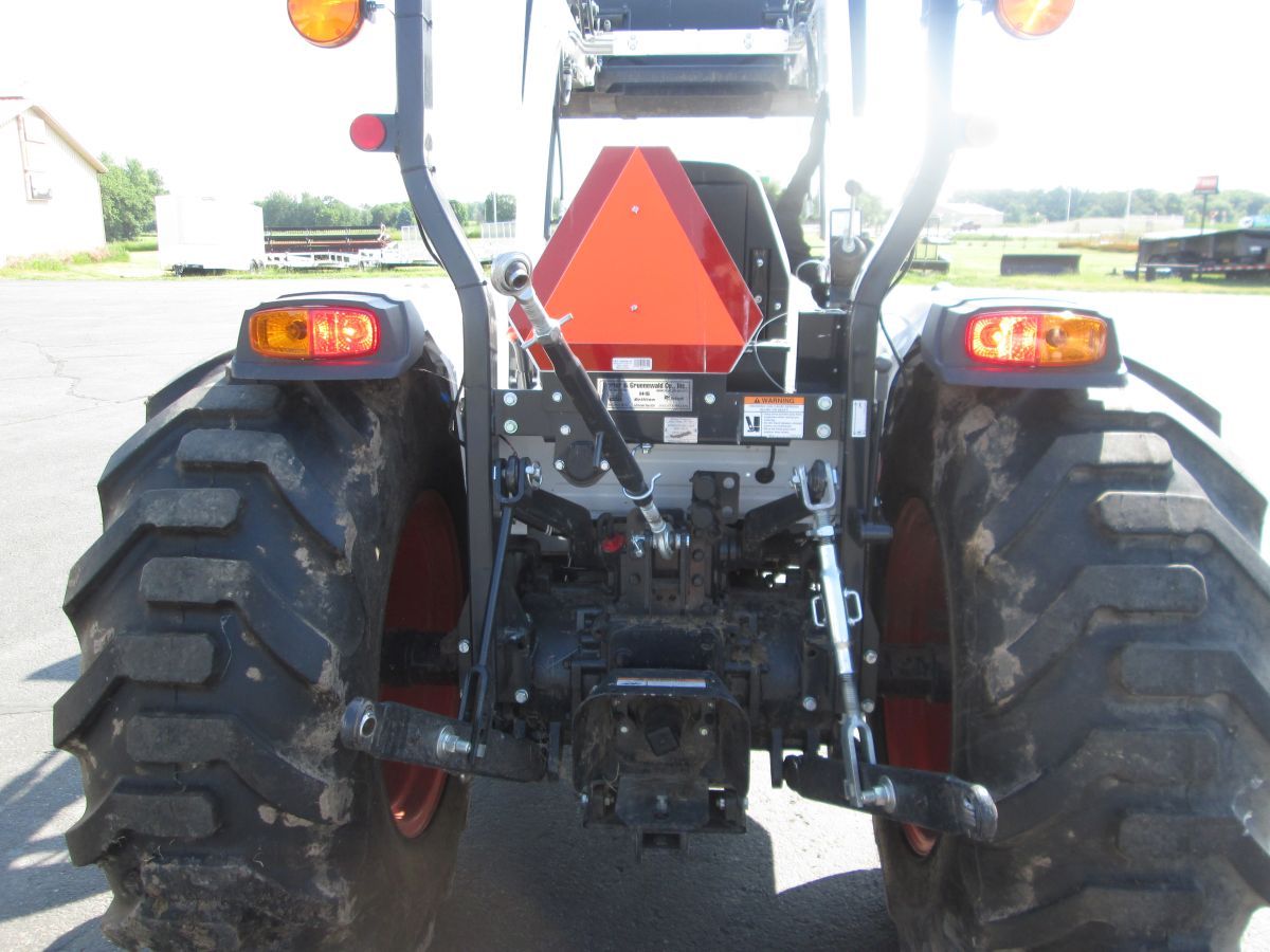 A red and black tractor is parked in a parking lot
