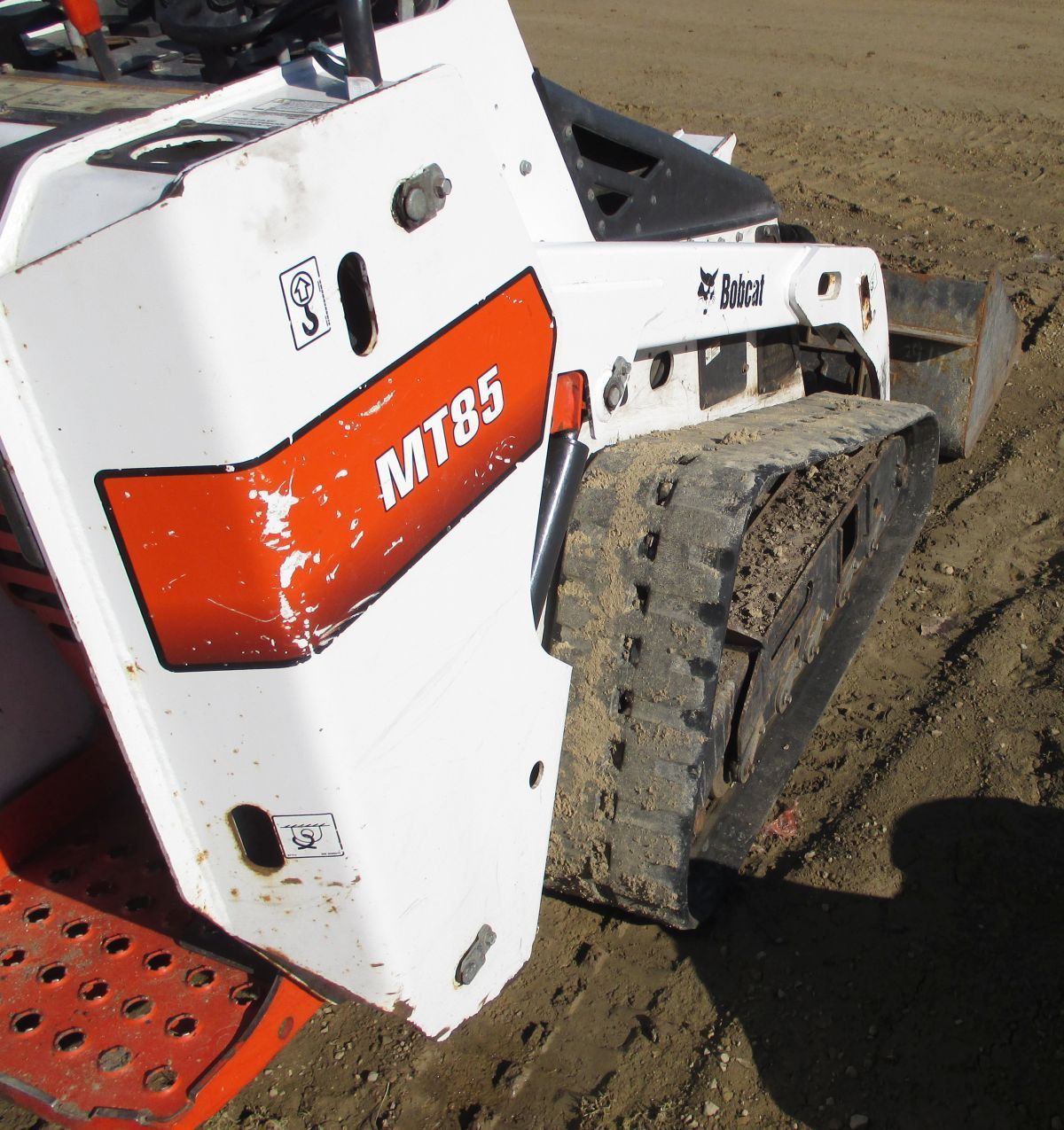 A white and orange mt85 tractor is sitting in the dirt