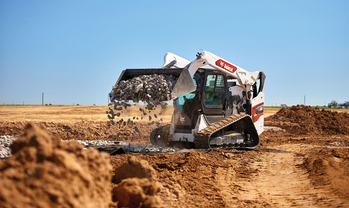 A bulldozer is loading dirt into a pile on a dirt road.