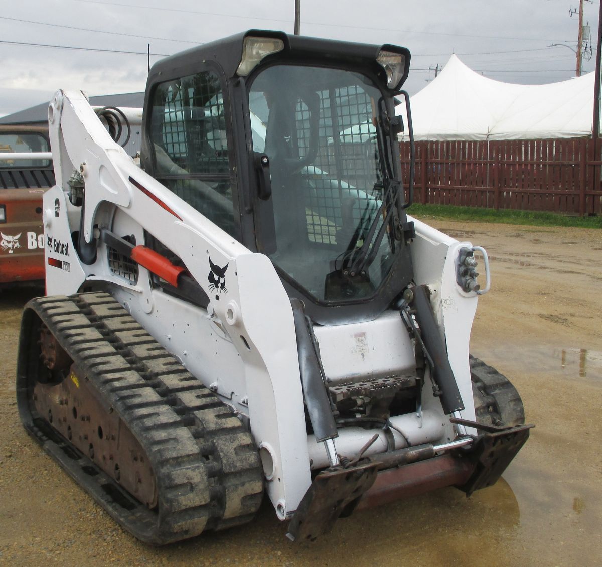 A bobcat tractor is parked in a dirt lot