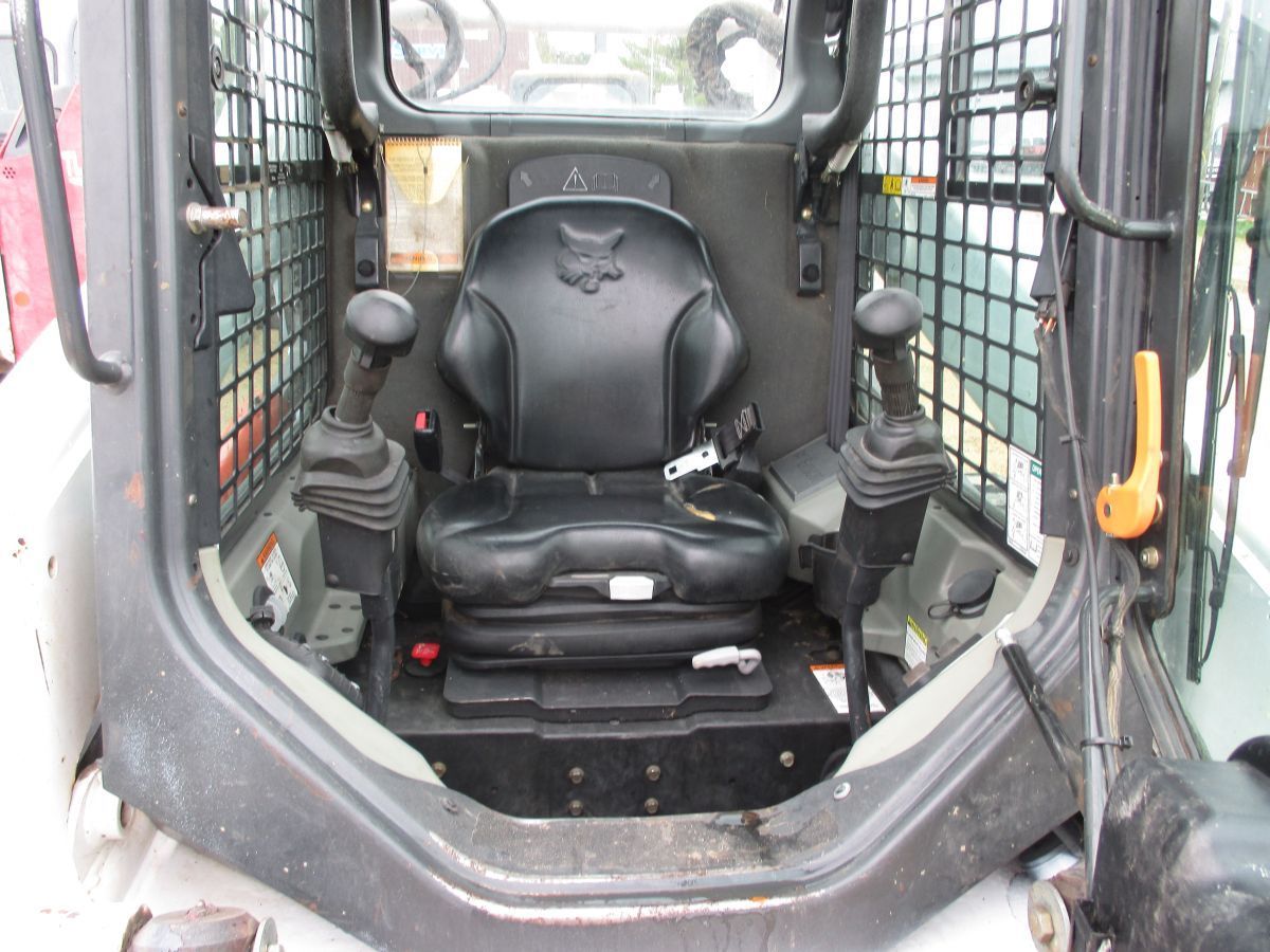 The inside of a bobcat skid steer with a black seat