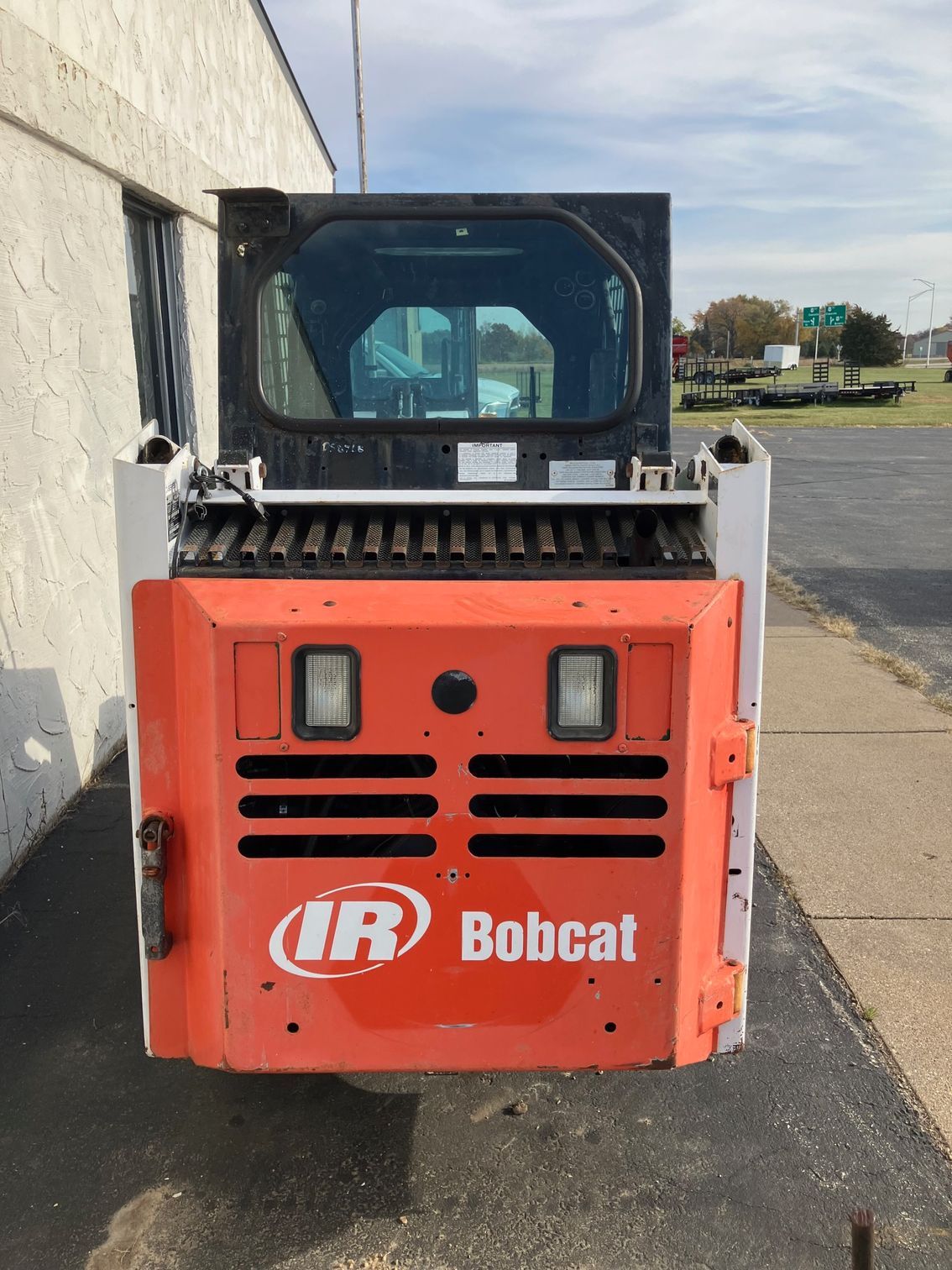 A bobcat is parked on the side of the road