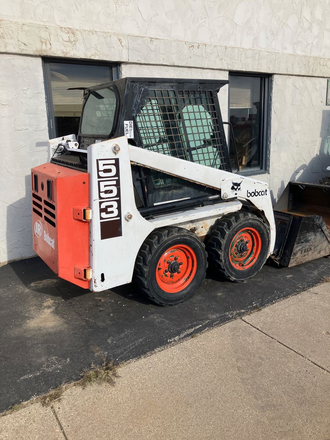 A bobcat skid steer is parked in front of a building.