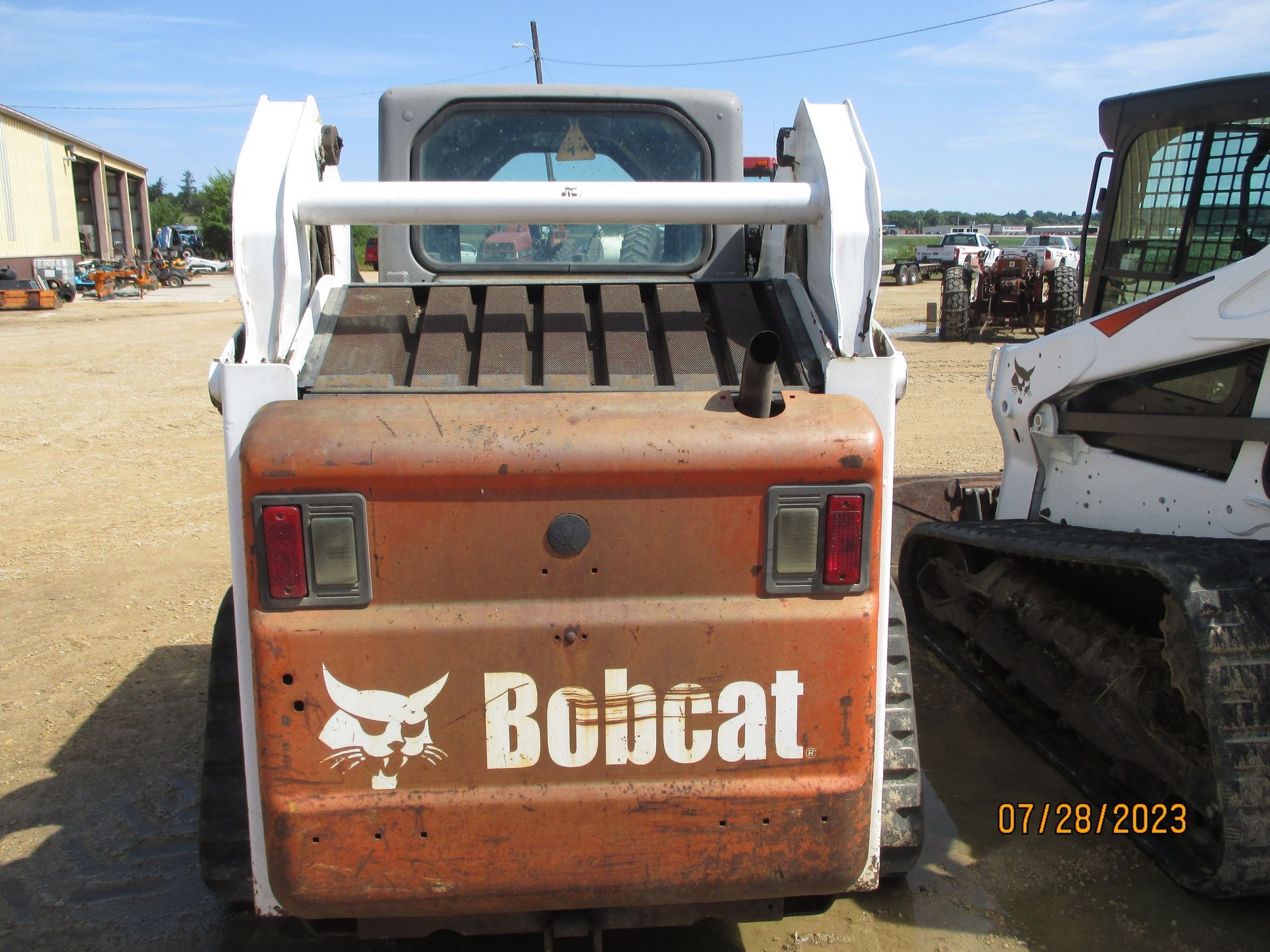 A bobcat tractor is parked in a dirt lot