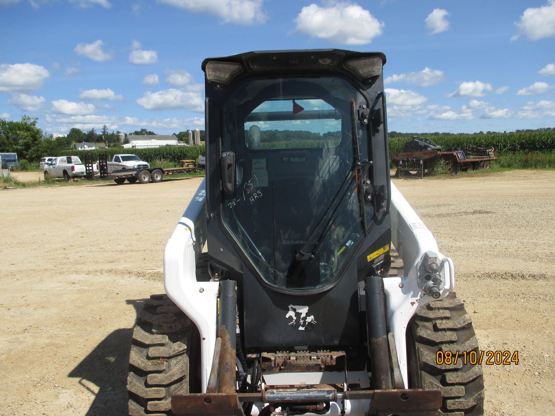 A bobcat tractor is parked in a dirt field