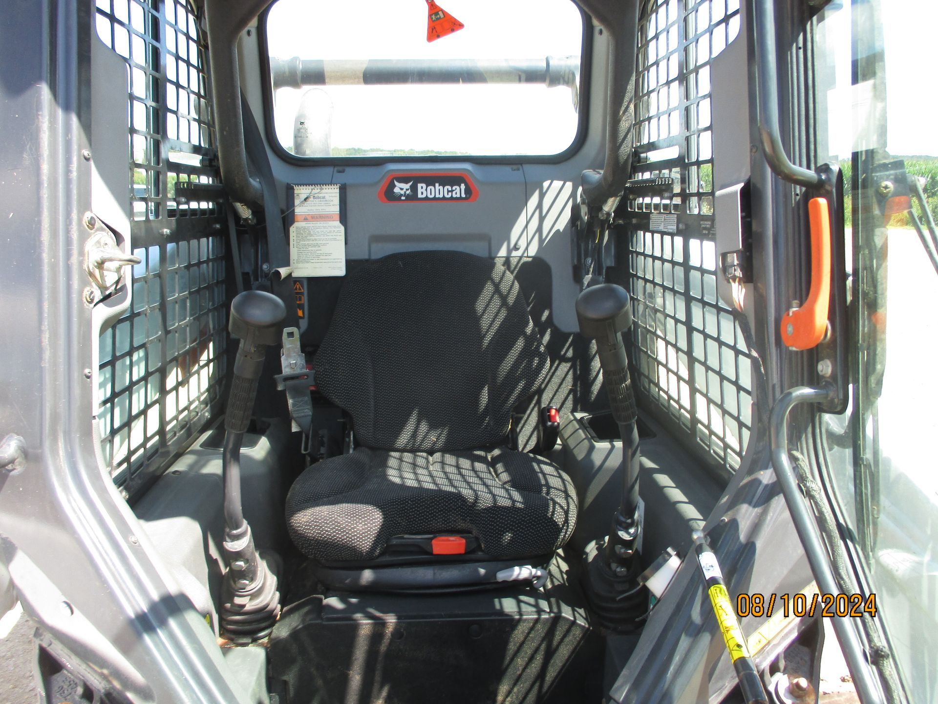 The inside of a bobcat with a black seat