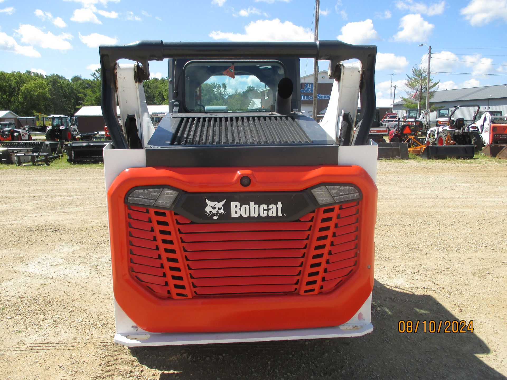 A bobcat tractor is parked in a dirt field