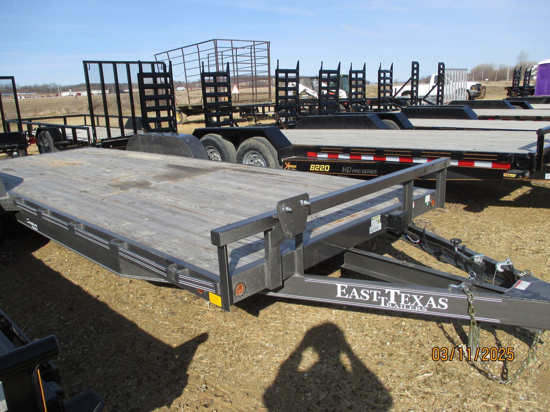 A row of trailers are parked in a dirt field.