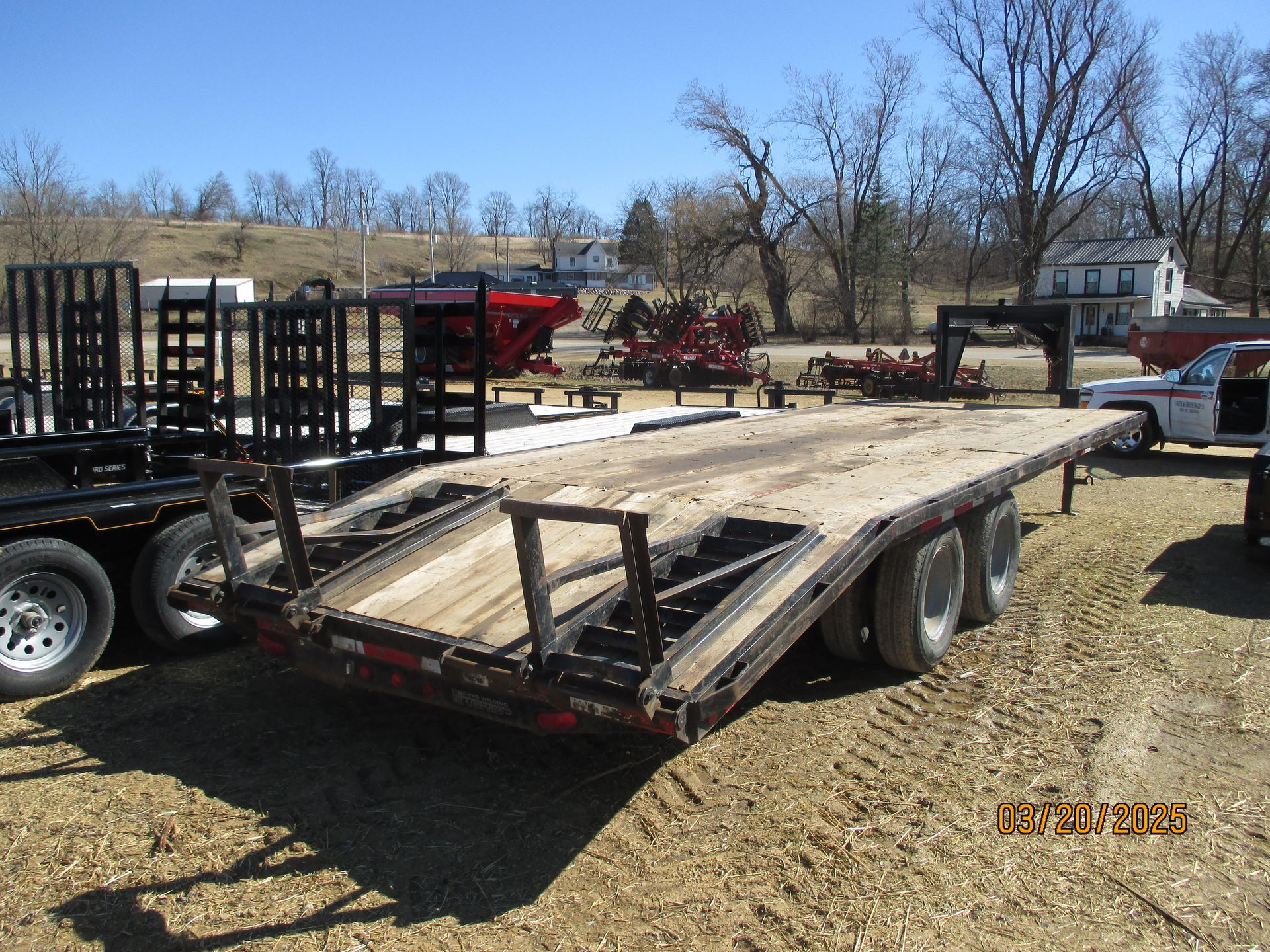 A flatbed trailer is parked in a dirt field