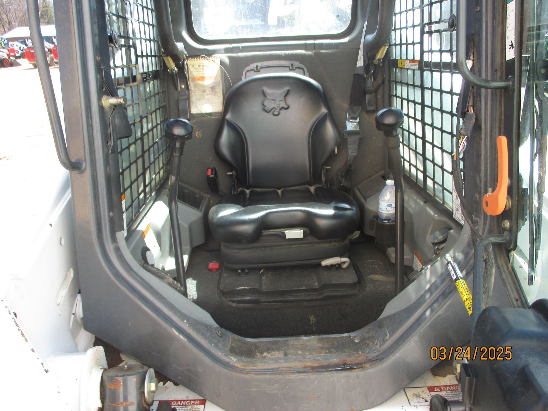 The inside of a bobcat skid steer with a black seat.