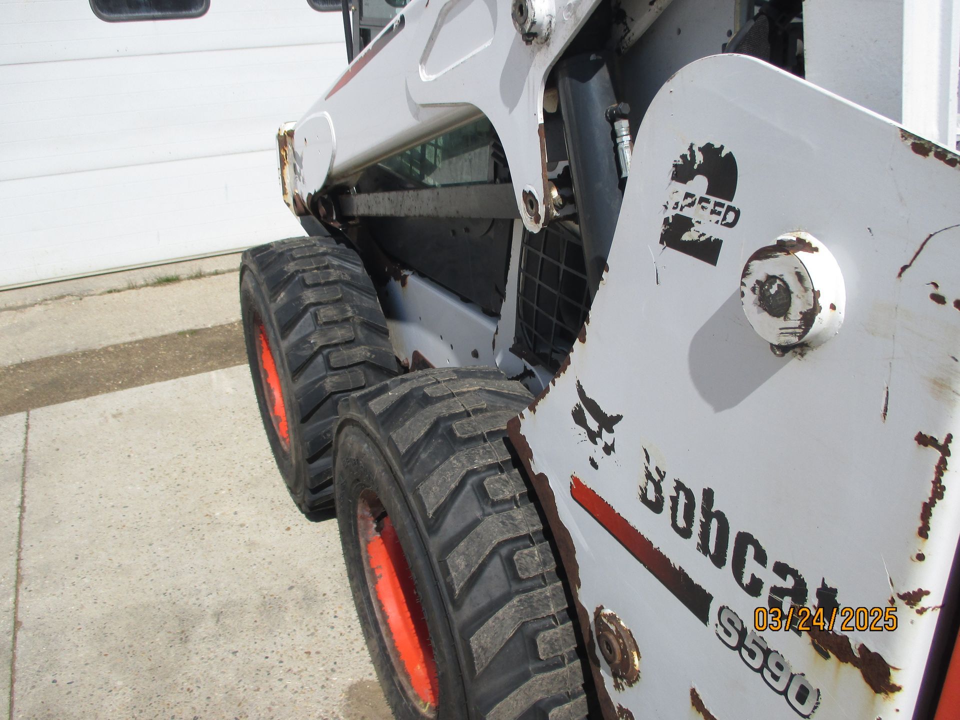 A bobcat skid steer is parked in front of a garage