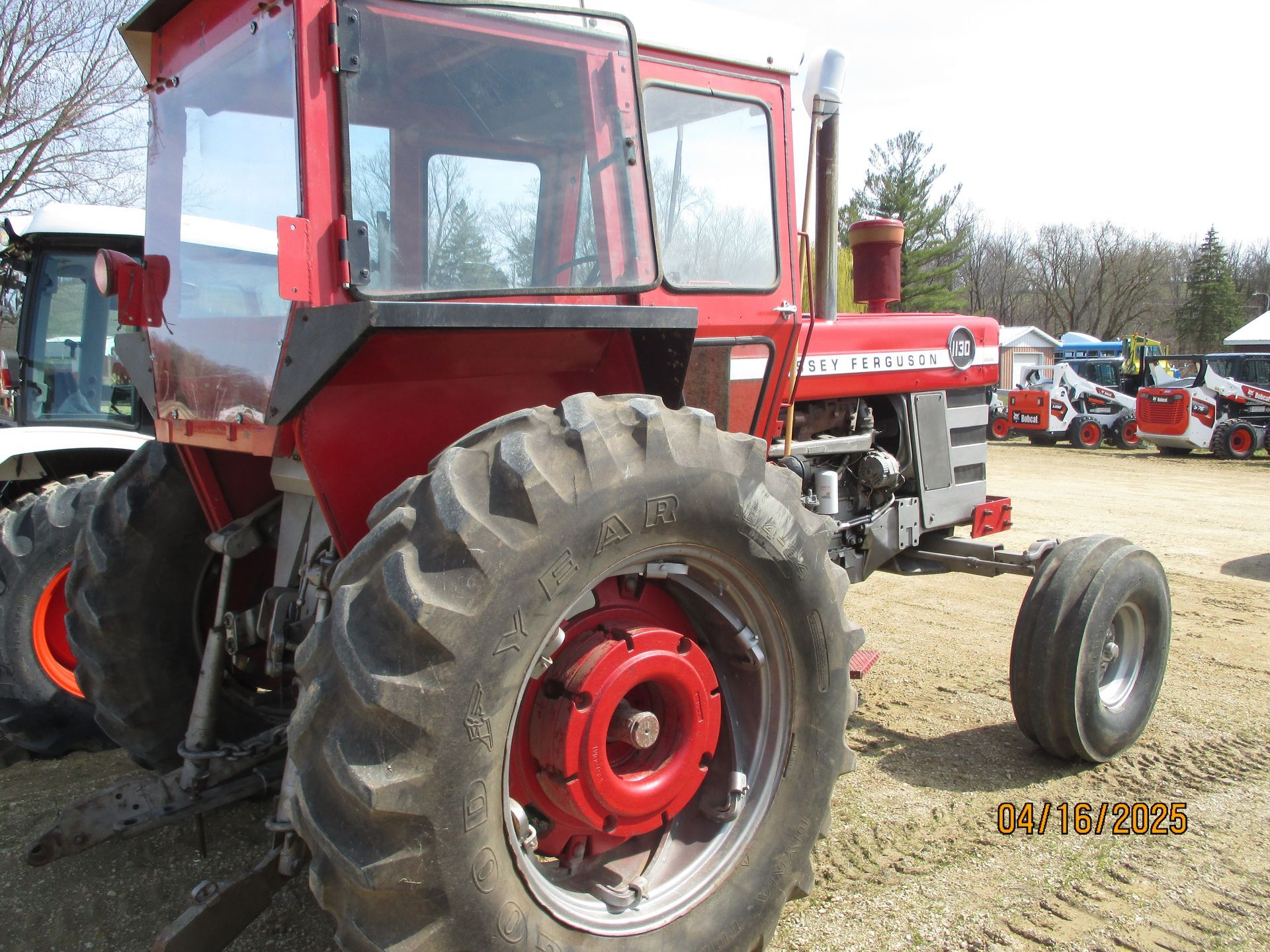 A red tractor is parked in a dirt field