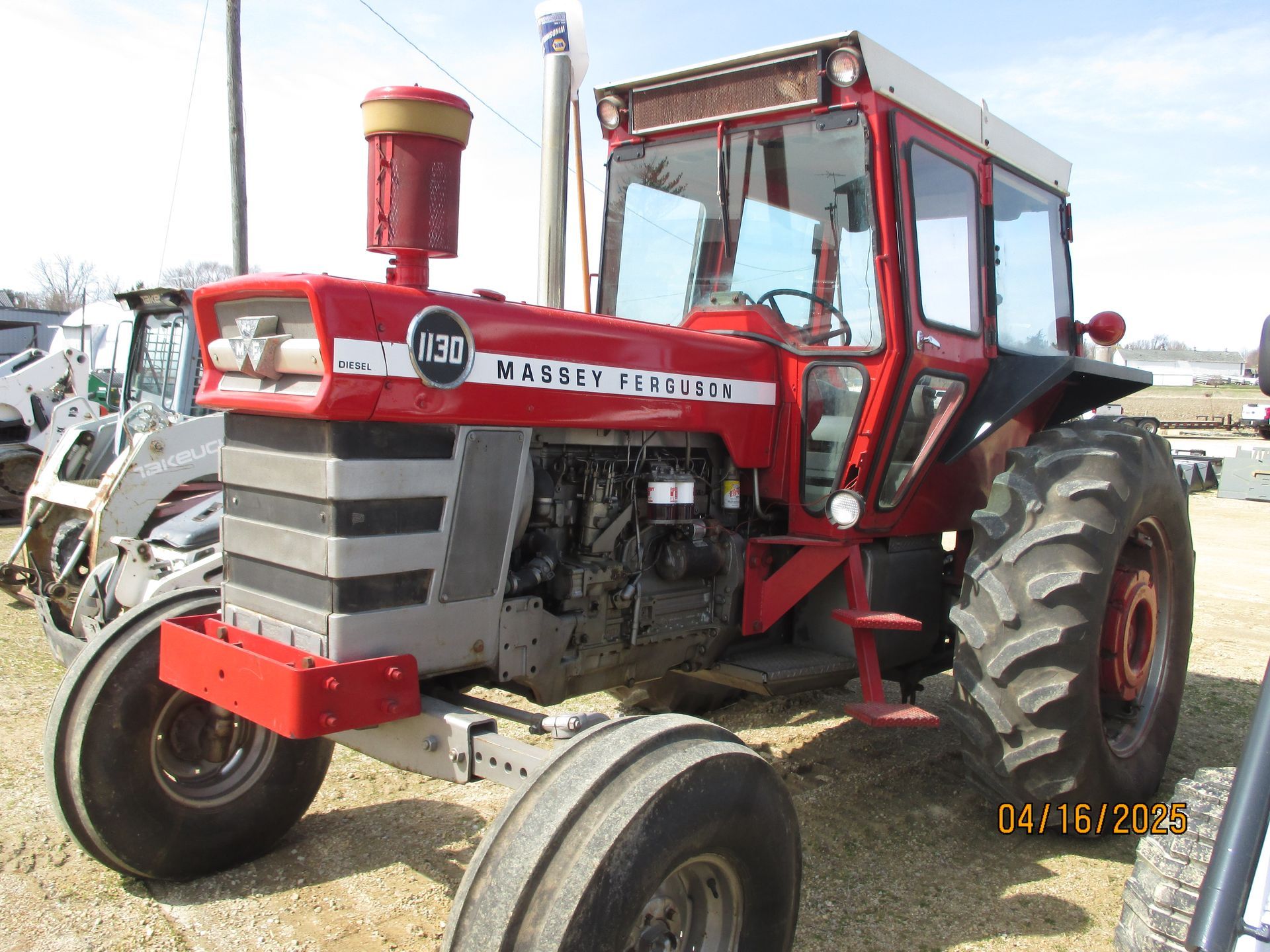 A red massey ferguson tractor is parked in a field