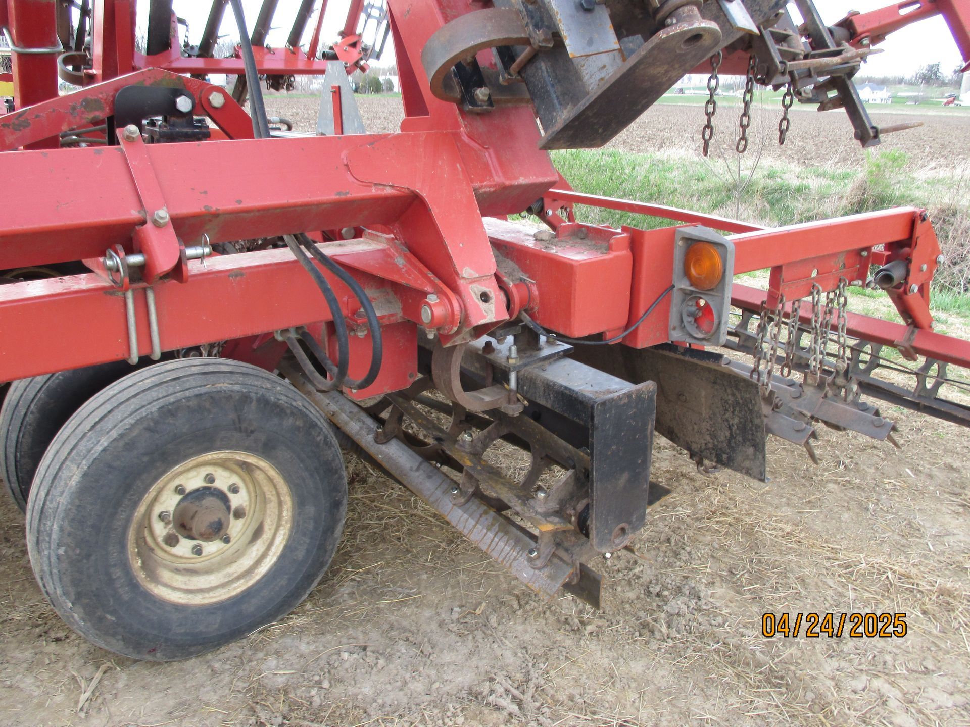 A red tractor is parked in a dirt field.