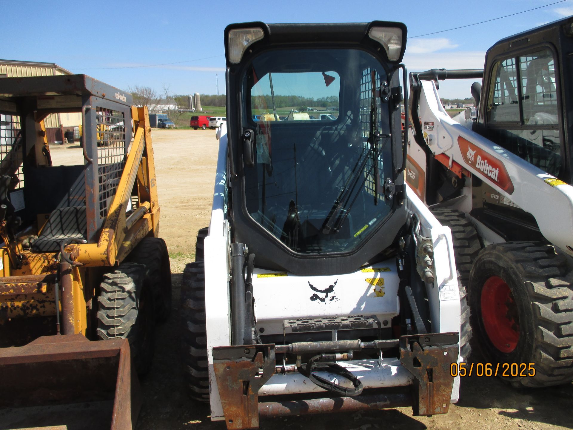 A bobcat tractor is parked in a dirt field