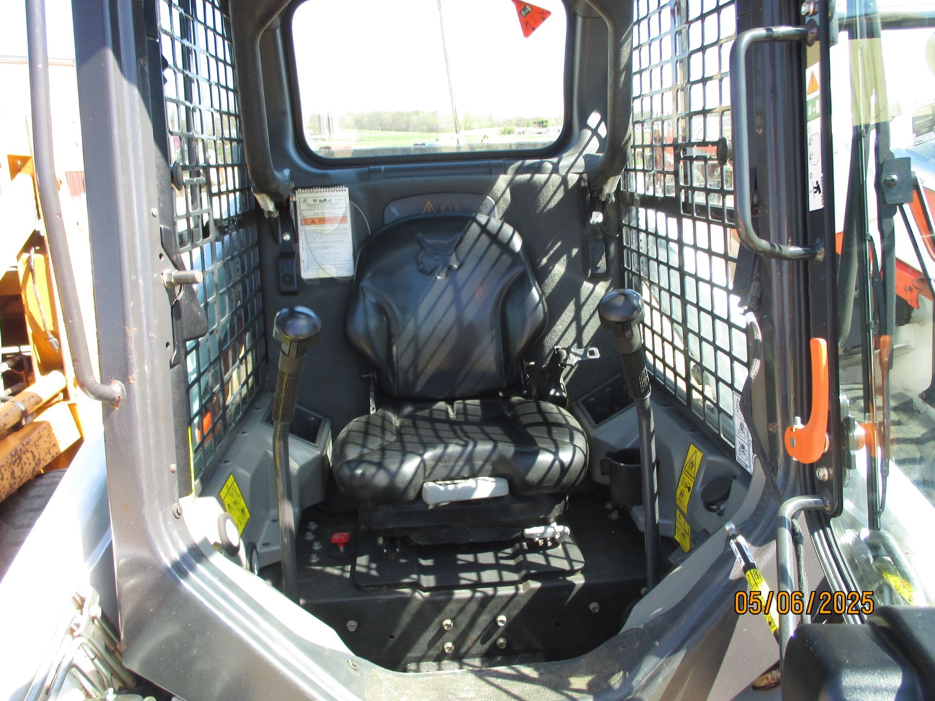 The inside of a skid steer with a black seat
