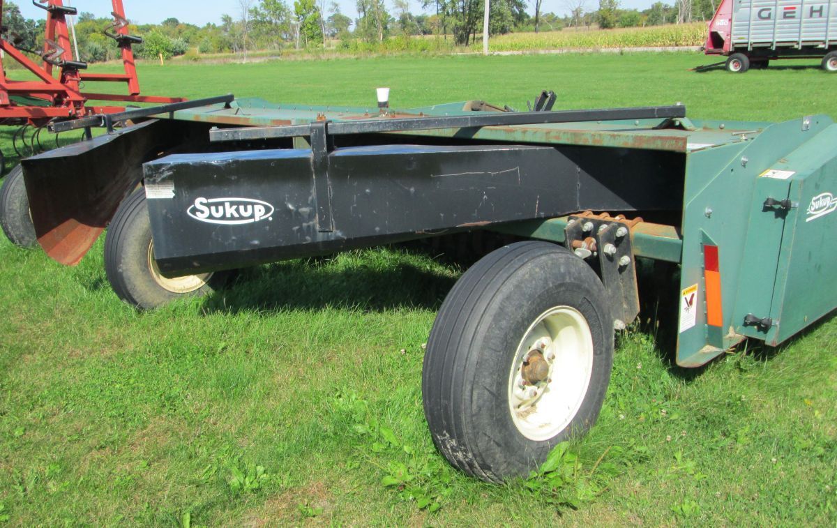 A green and black tractor is parked in a grassy field.